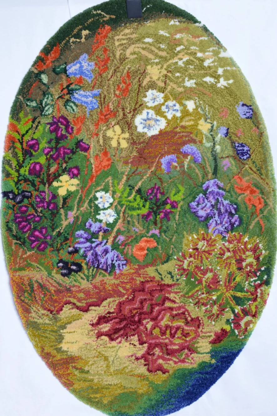 Colorful floral rug with various types of meadow bog flowers, moss,  and greenery arranged in an oval shape.
