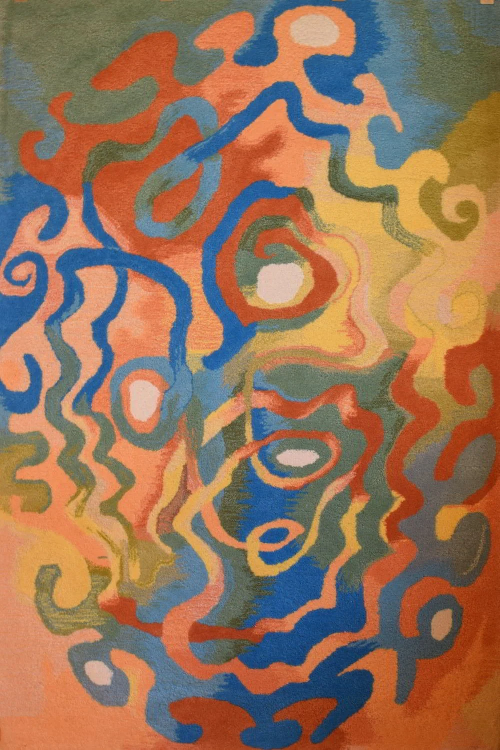 Abstract hand crafted tufted wool pile textile with swirling lines in shades of orange, blue, green, yellow, and white.