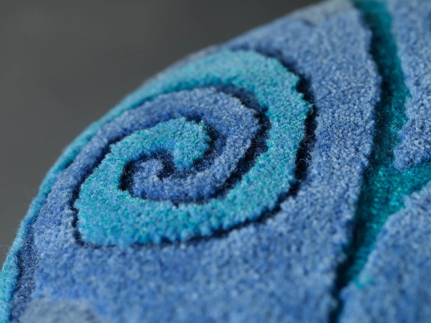 Close-up of a blue hand tufted textile stool top with a textured surface.