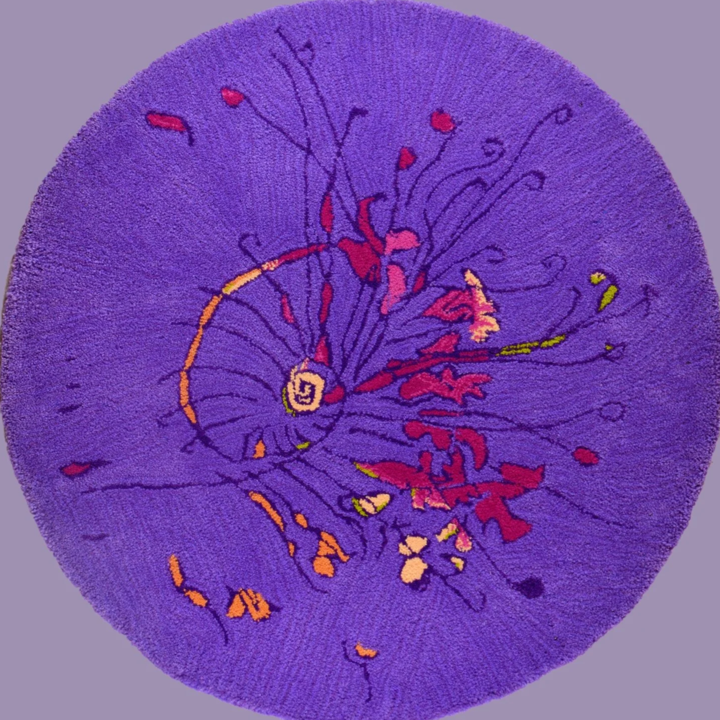 A round purple rug with abstract, colorful lines and shapes resembling a spiral, with red, yellow, pink, and black accents.