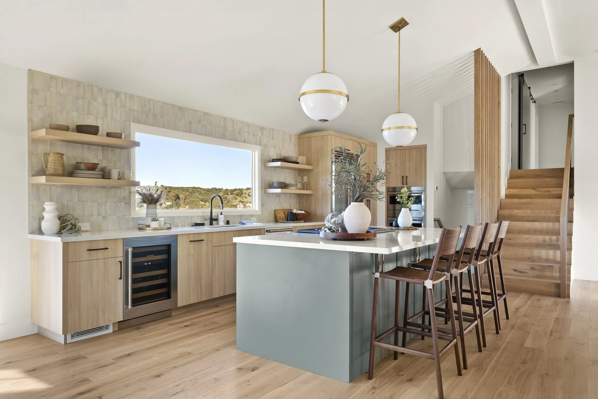 Kitchen renovation in Tiburon designed by Marin interior designer Studio SQUIRE featuring white oak custom cabinets, open shelving, a sage green island, and views.