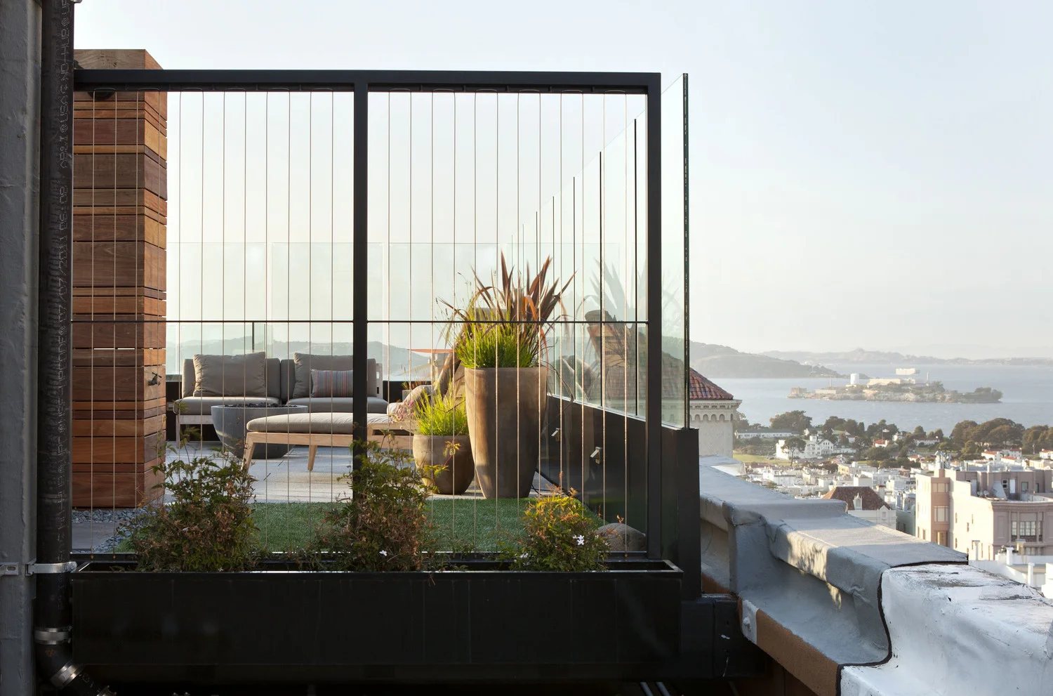 Outdoor Rooftop in a San Francisco home designed by Marin interior designer Studio SQUIRE featuring Glass Windscreen Panels, Artificial Turf, Outdoor Seating, and Planter Box