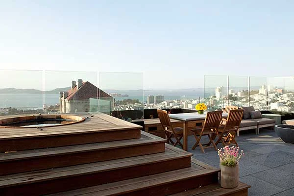 Outdoor Rooftop in a San Francisco Penthouse designed by Marin interior designer Studio SQUIRE featuring Glass Windscreen Panels, Platform Hot Tub, Outdoor Dining Table and Outdoor Dining Chairs