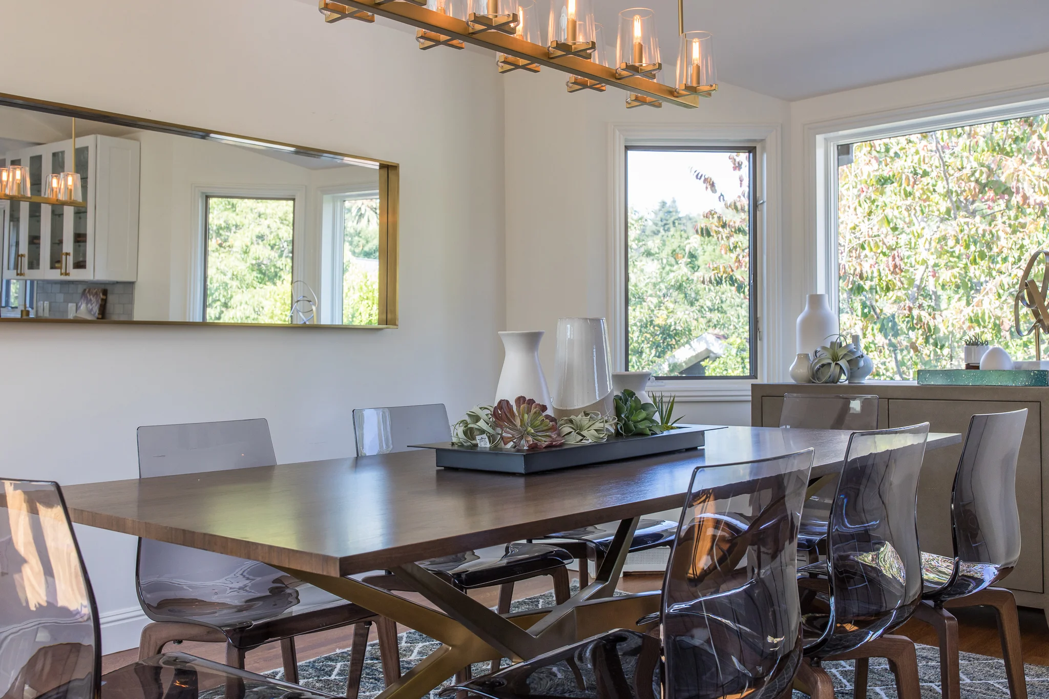 Dining Room in Mill Valley designed by Marin interior designer Studio SQUIRE featuring a Wood Table, Clear Acrylic Chairs, Brass Chandelier, and Rectangle Mirror
