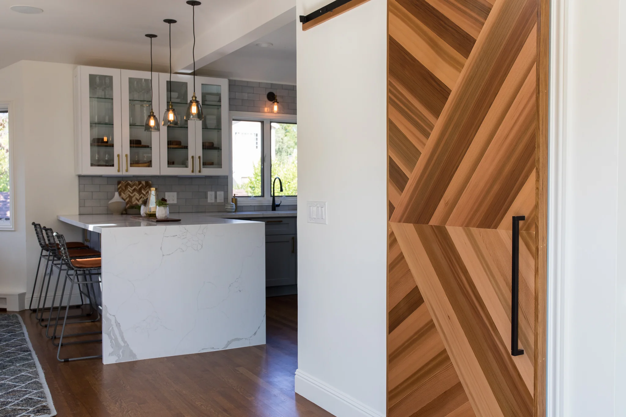 Custom Barn Door in Mill Valley designed by Marin interior designer Studio SQUIRE featuring Wood Barn Door, Glass Pendants, Waterfall Countertop, and Subway Tile