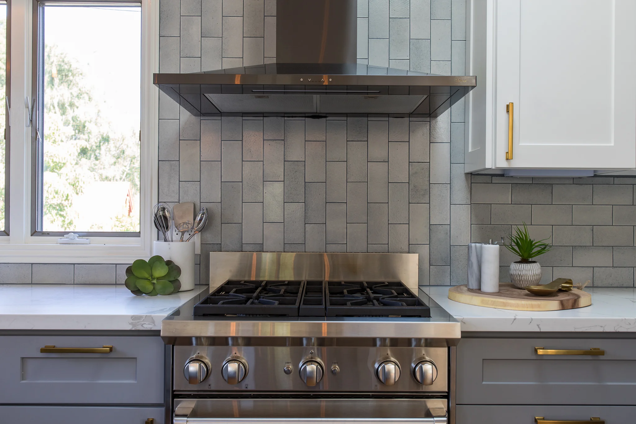 Kitchen renovation in Mill Valley designed by Marin interior designer Studio SQUIRE featuring Quartz Countertop, Subway Tile Backsplash, Grey Cabinets, White Cabinets, Brass Hardware, and Stainless Steel Appliances