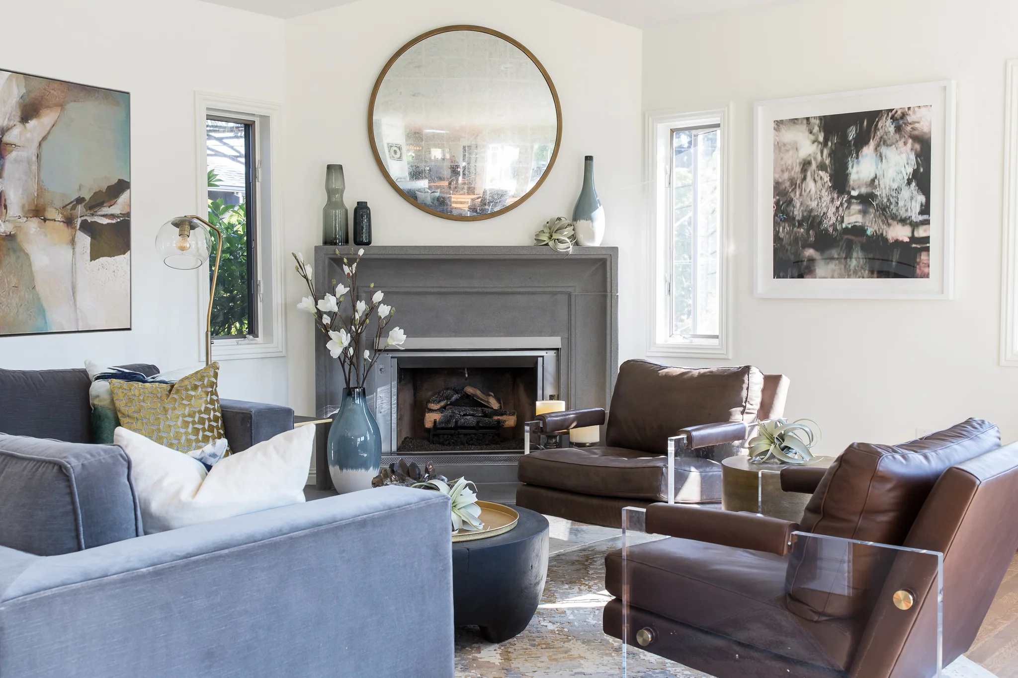 Living Room in Mill Valley designed by Marin interior designer Studio SQUIRE featuring Leather Chairs, Upholstered Sofa, Grey Modern Fireplace, Area Rug, and Wood Round Mirror