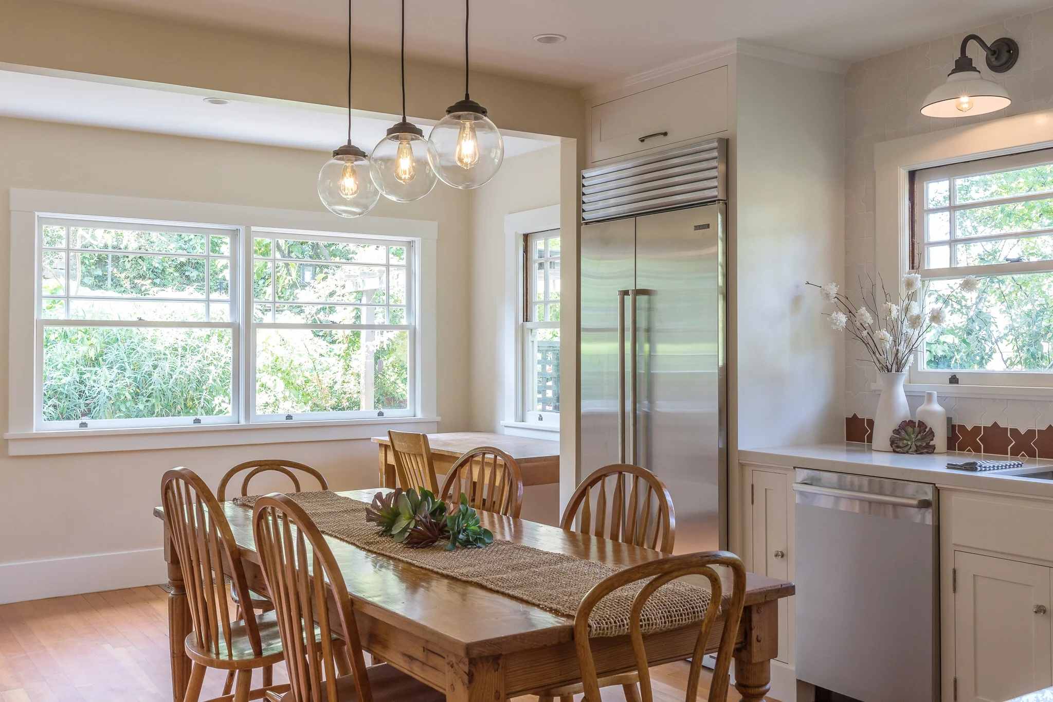 Kitchen renovation in Sausalito designed by Marin interior designer Studio SQUIRE featuring Moroccan Tile, White Cabinets, Wood Dining Table, Wood Dining Chairs, Stainless Steel Appliances, and Glass Pendant Lighting