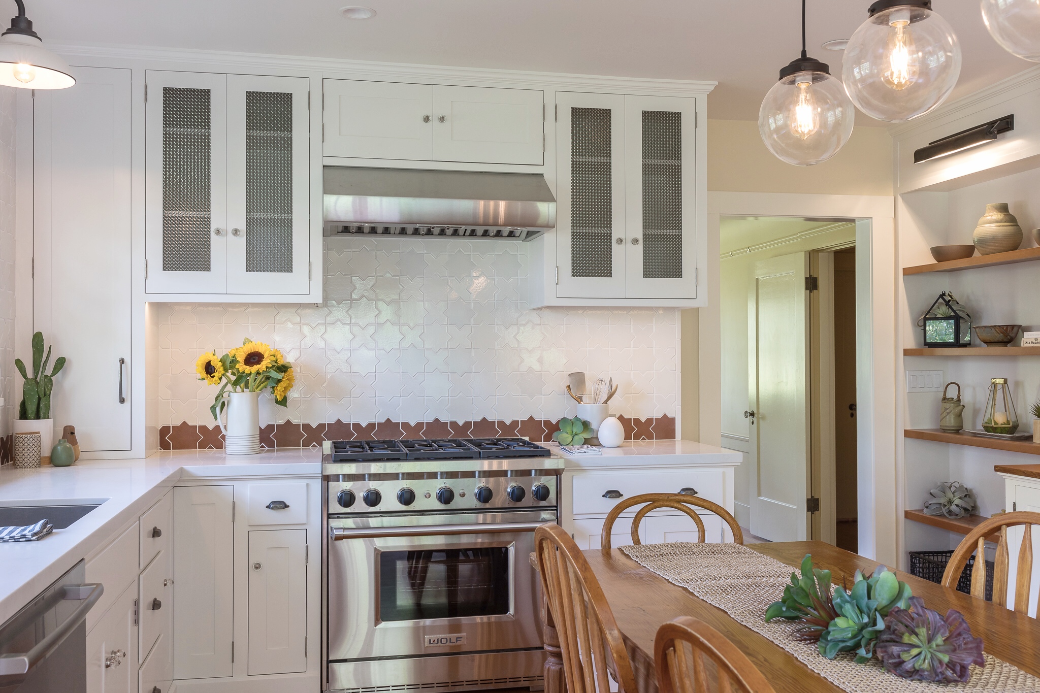 Kitchen renovation in Sausalito designed by Marin interior designer Studio SQUIRE featuring Moroccan Tile, Stainless Steel Appliances, White Cabinets, Wood Dining Table, Wood Dining Chairs, and Wood Shelves
