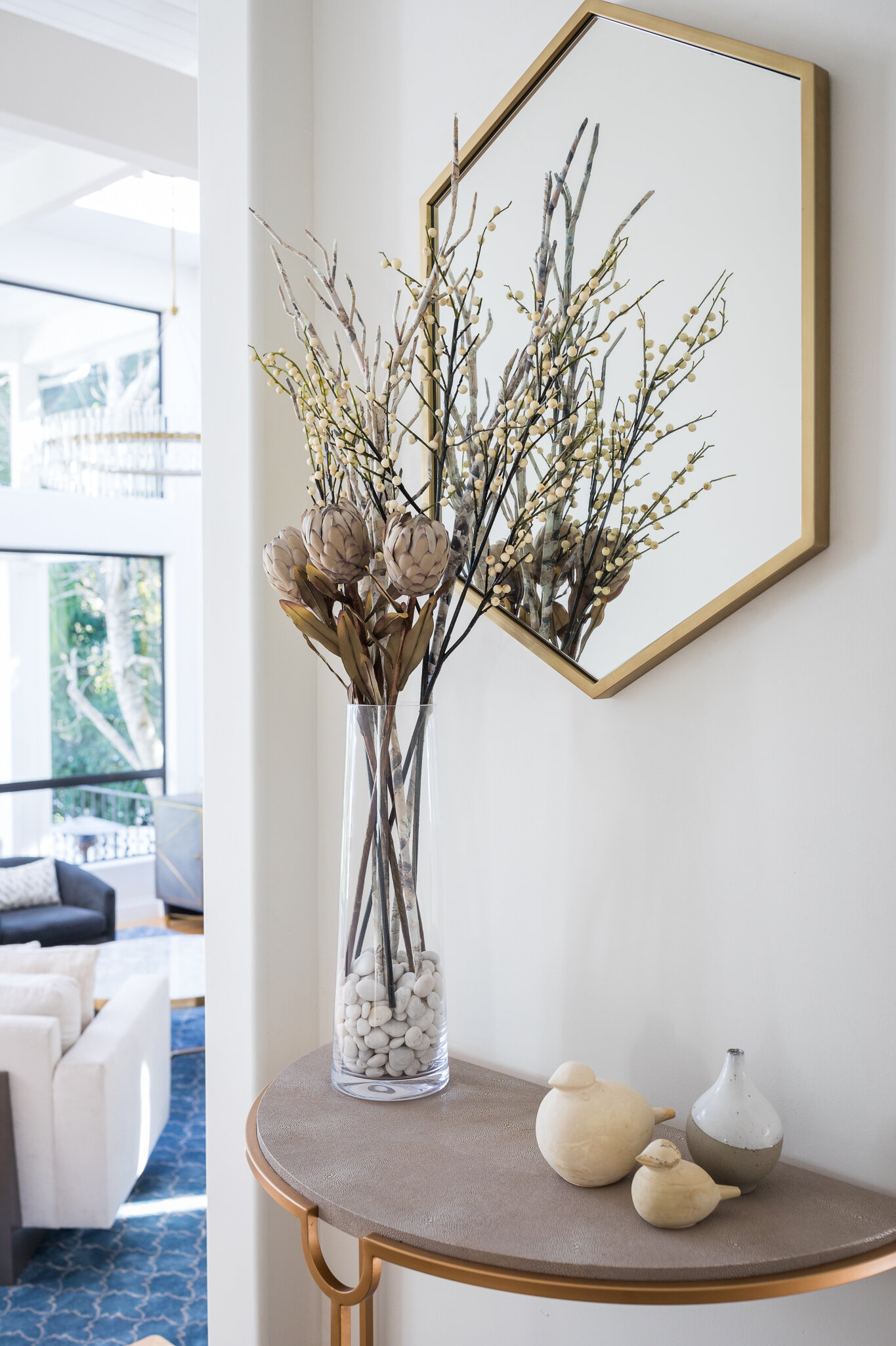 Foyer in a Mill Valley home designed by Marin interior designer Studio SQUIRE featuring a modern demilune table, floral arrangement, hexagon mirror, and brass accents.