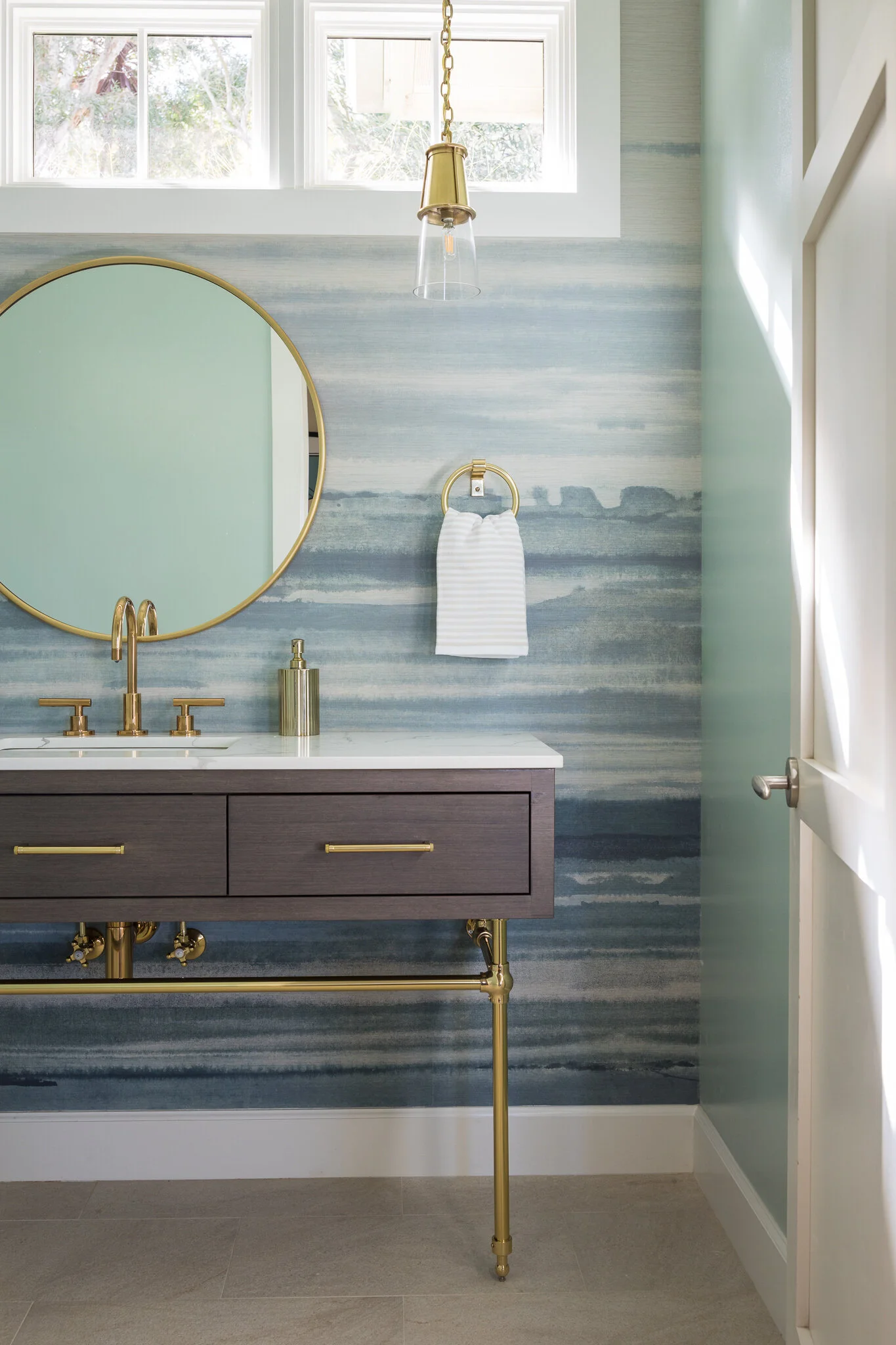 Powder renovation in Tiburon designed by Marin interior designer Studio SQUIRE featuring a coastal-inspired wall mural, round mirror, and brass fixtures and hardware.