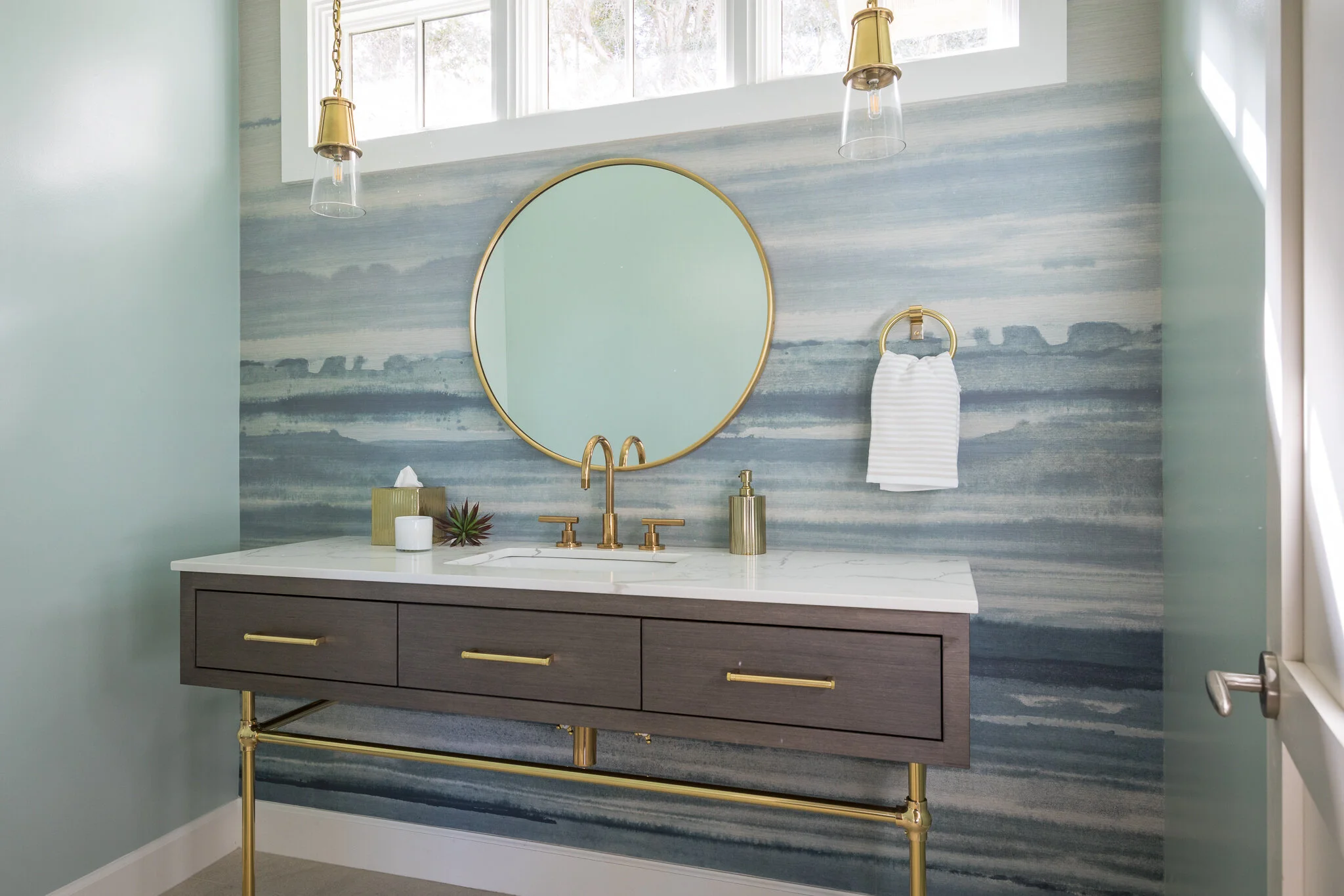 Powder renovation in Tiburon designed by Marin interior designer Studio SQUIRE featuring a coastal-inspired wall mural, round mirror, and brass fixtures and hardware.