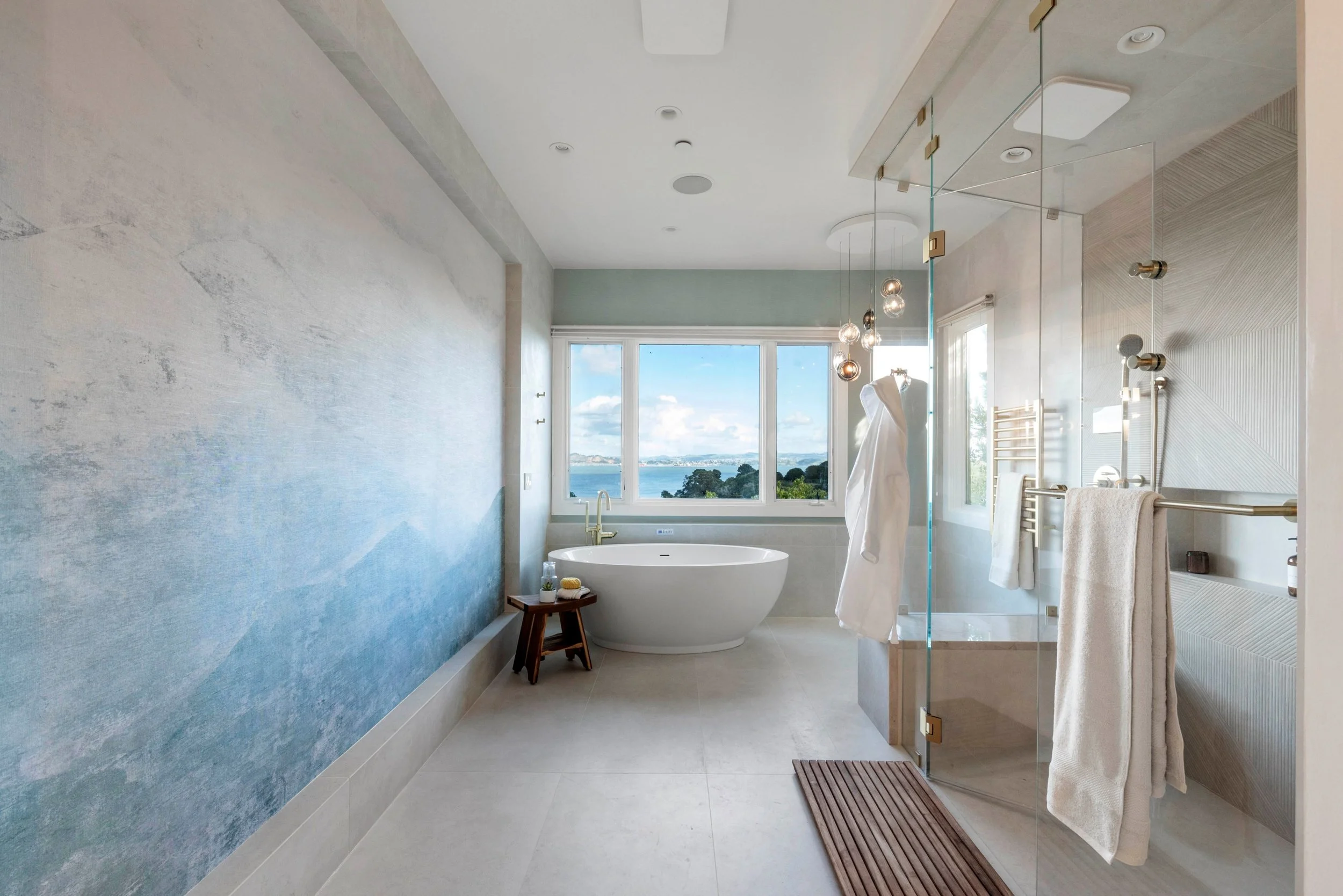 Luxury primary bathroom renovation in Tiburon designed by Marin interior designer Studio SQUIRE featuring a coastal wallpaper mural, freestanding soaking tub, steam shower, and views of the San Francisco Bay.