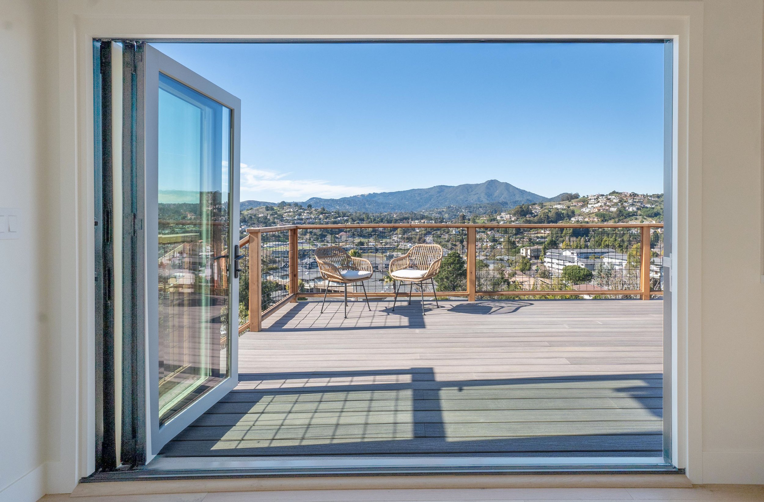 Outdoor living space designed by Marin interior designer Studio SQUIRE for a Tiburon home featuring folding glass door to deck with a view of Mount Tamalpais.