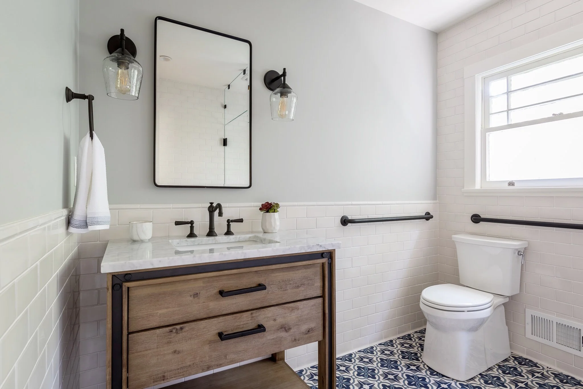 Bathroom renovation in Sausalito designed by Marin interior designer Studio SQUIRE featuring a Wood Vanity, Black Metal Mirror, Black Fixtures, Subway Tile, and Moroccan Tile
