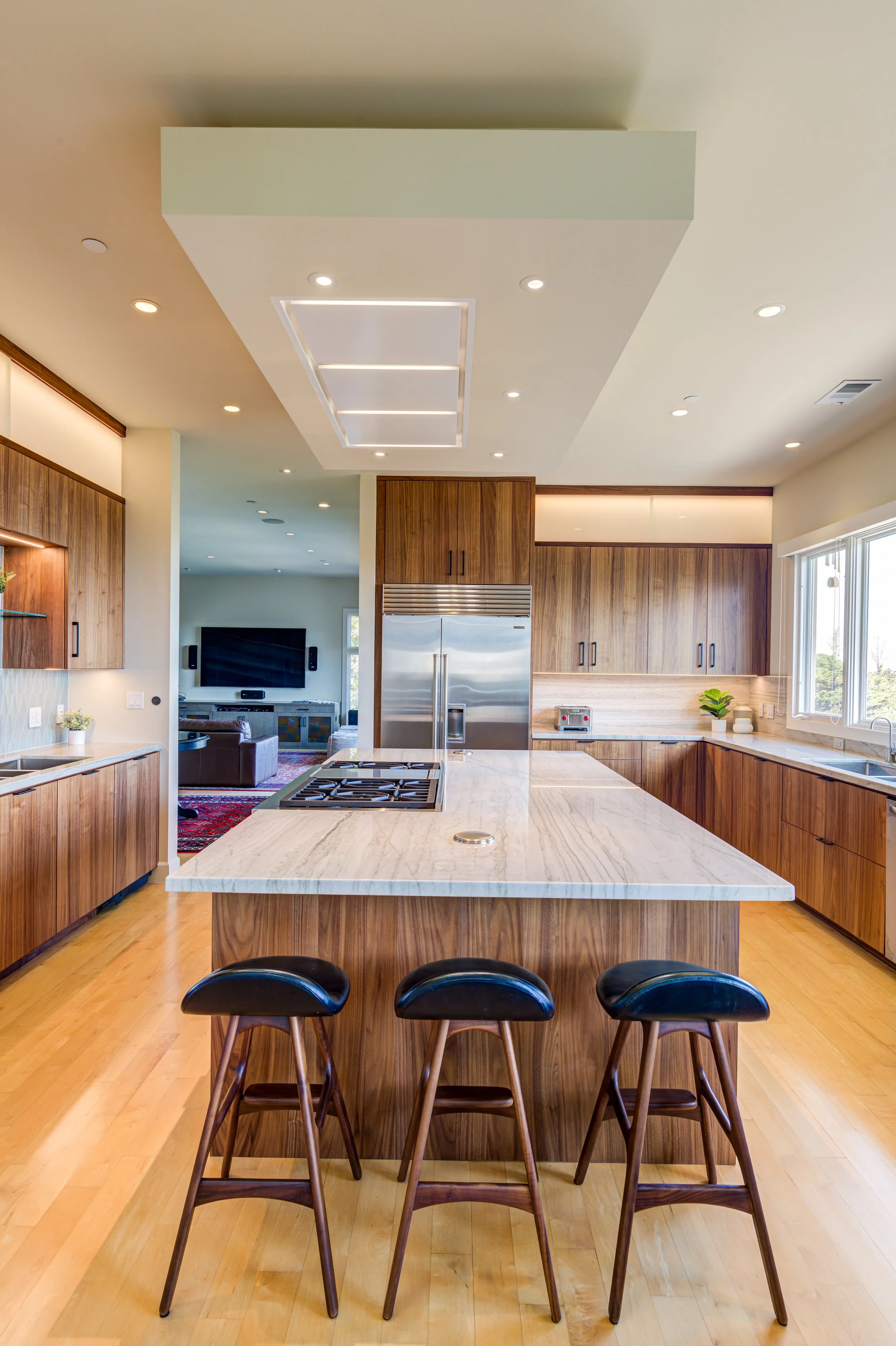 Luxury kitchen renovation in Belvedere-Tiburon designed by Marin interior designer Studio SQUIRE featuring walnut cabinets, matte black, cabinet hardware, quartzite countertops, Subzero Wolf appliances, and panoramic views of the San Francisco Bay.