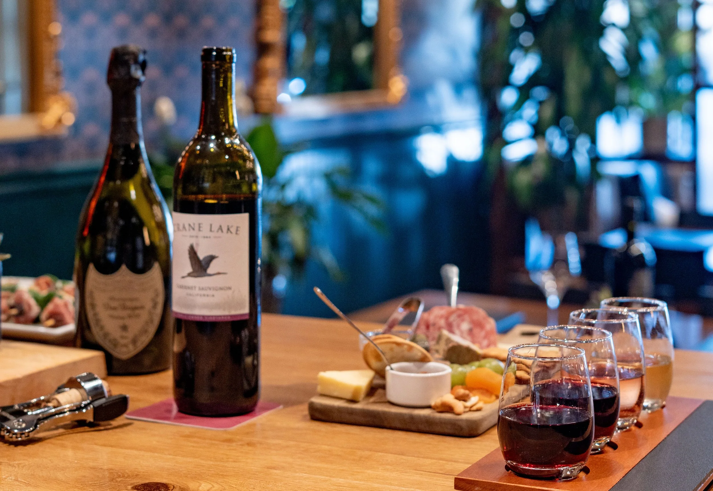 Commercial wine bar renovation in Belvedere-Tiburon designed by Marin interior designer Studio SQUIRE featuring Wood High Top Table, Patterned Wallpaper, Wood Paneling, and Brass Mirrors