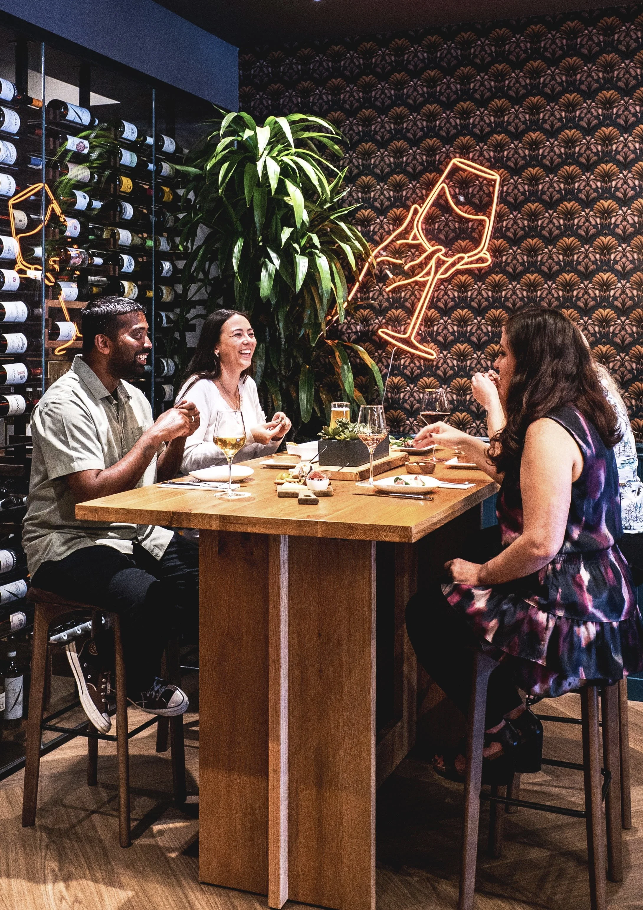 Commercial wine bar renovation in Belvedere-Tiburon designed by Marin interior designer Studio SQUIRE featuring Wood High Top Table, Barstools, Patterned Wallpaper, and Neon Light
