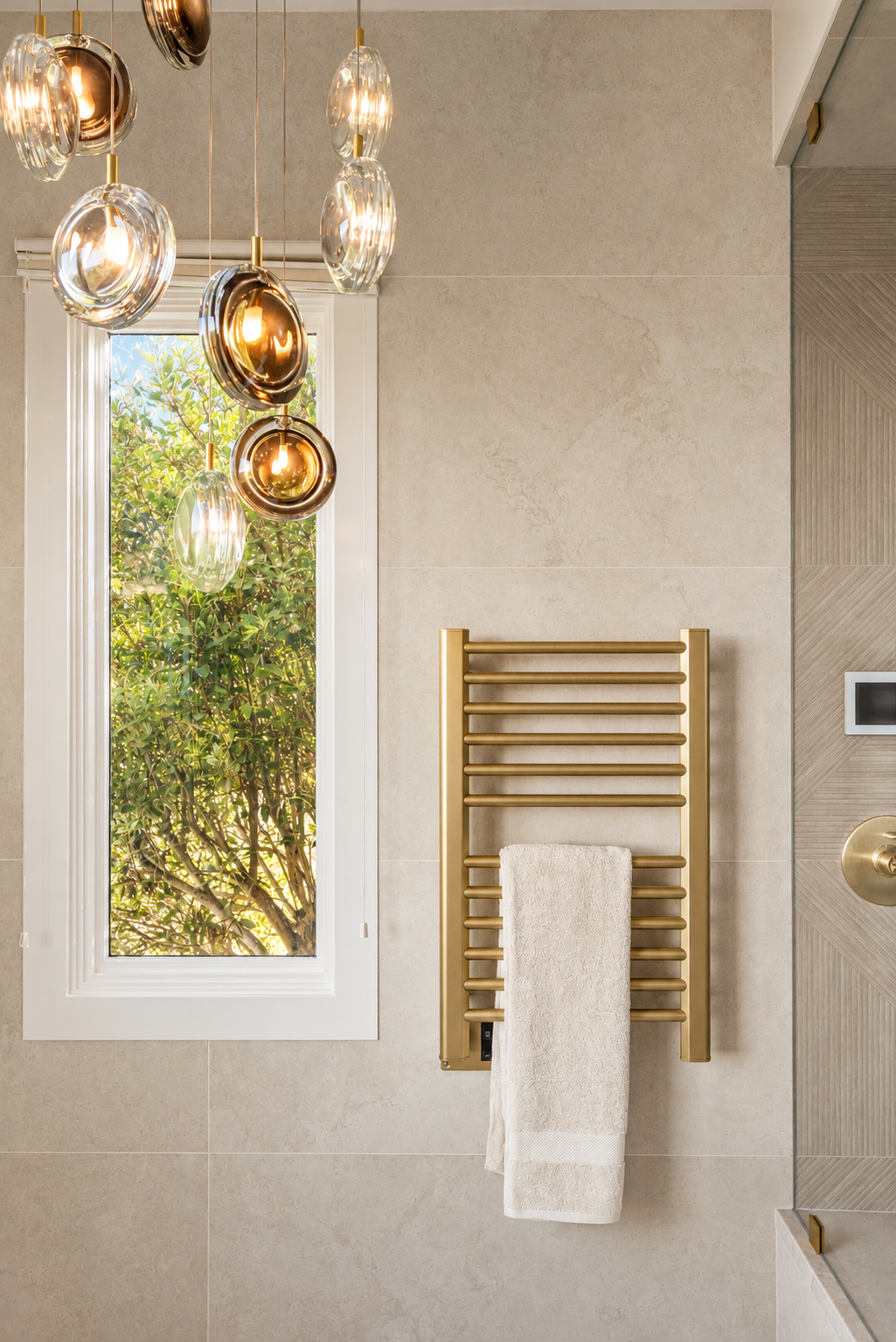 Luxury primary bathroom renovation in Tiburon designed by Marin interior designer Studio SQUIRE featuring a coastal modern design, satin brass towel warmer, and modern chandelier.