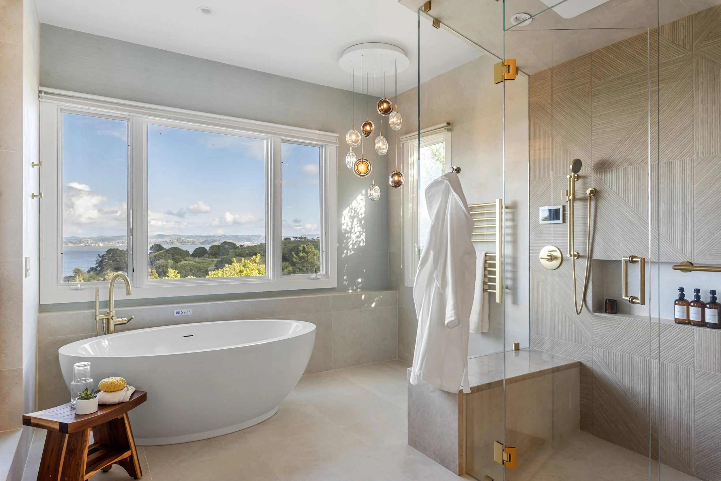 Bathroom renovation in Belvedere-Tiburon designed by Marin interior designer Studio SQUIRE featuring heated tile flooring, a free standing tub, steam shower, towel warmer, and sweeping views of the San Francisco Bay.