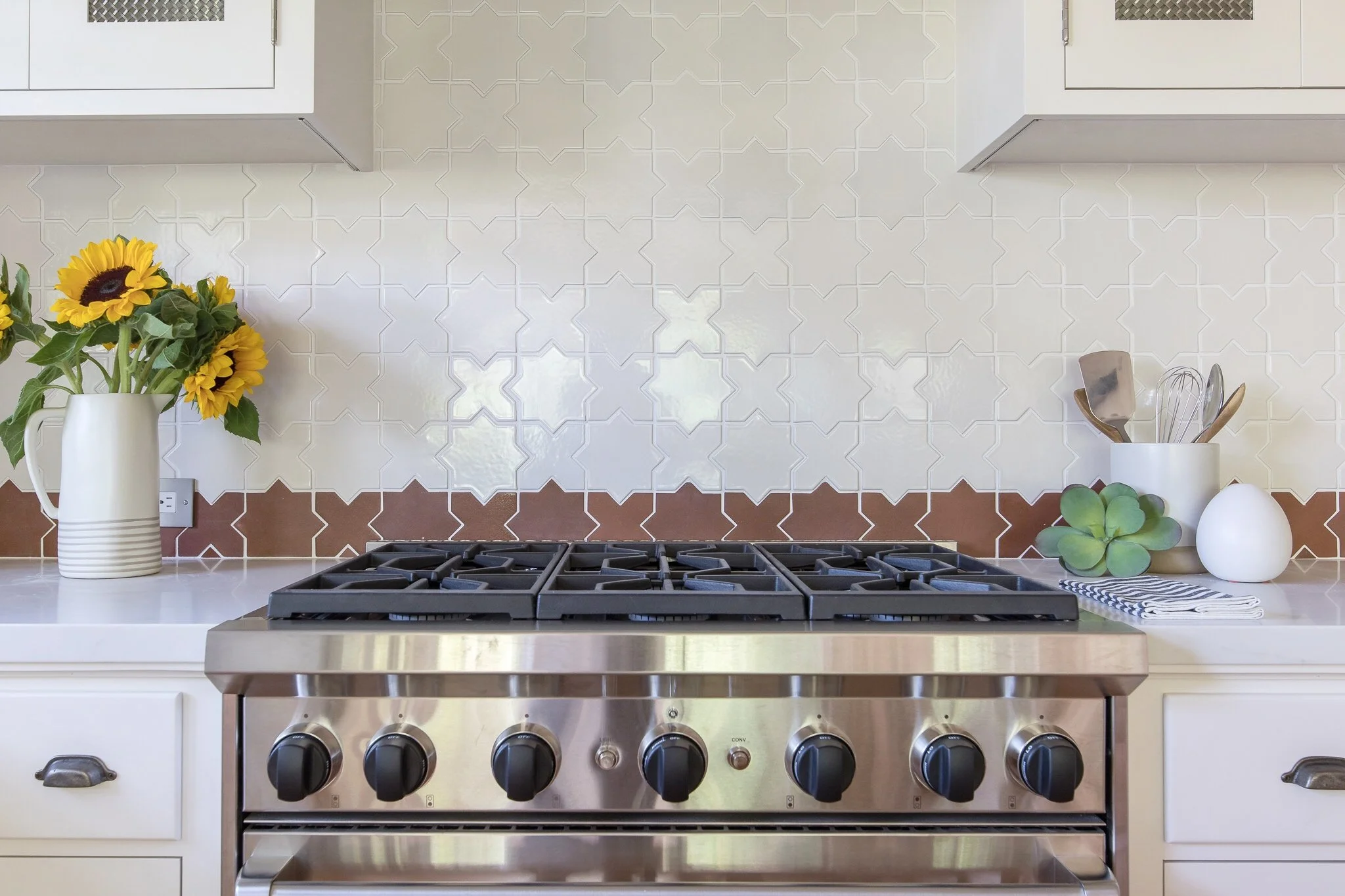 Kitchen renovation in Sausalito designed by Marin interior designer Studio SQUIRE featuring handmade star and cross tile, quartz countertop, range stove top, and oil-rubbed bronze, hardware