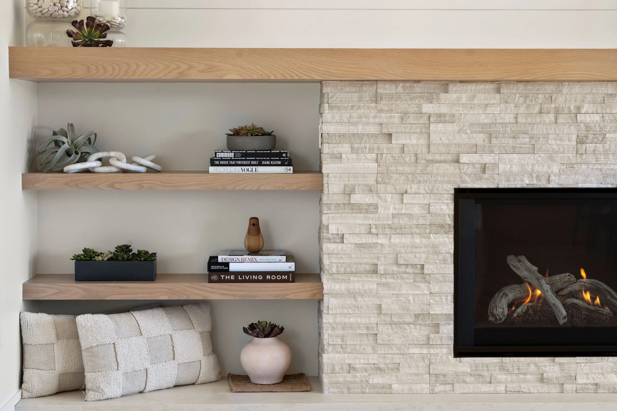 Custom fireplace renovation in Belvedere-Tiburon designed by Marin interior designer Studio SQUIRE featuring a modern white oak mantel and shelving and a ledgestone fireplace surround.