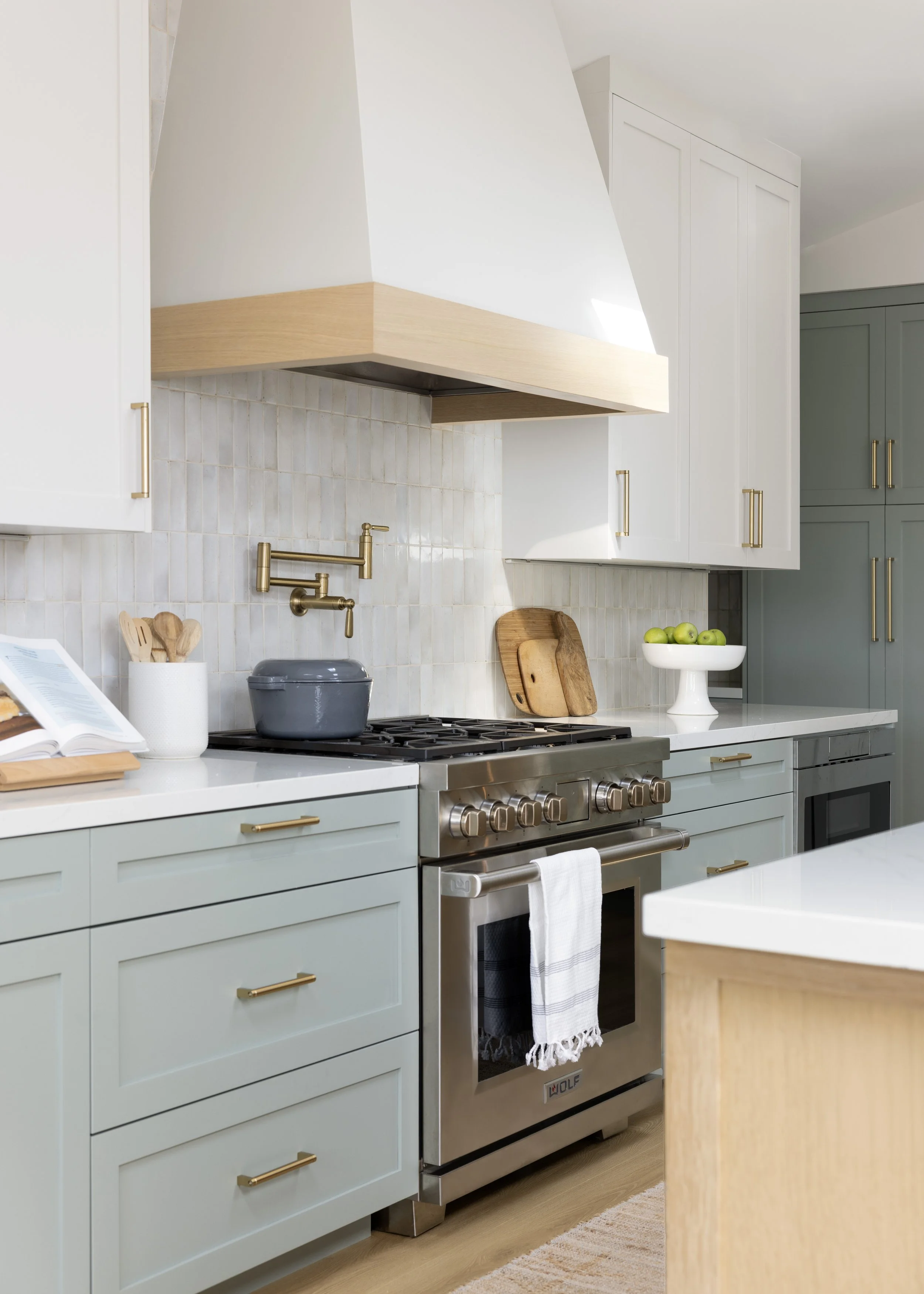 Kitchen renovation in Mill Valley designed by Marin interior designer Studio SQUIRE featuring Sage Green Cabinetry, Custom Range Hood, Brass Fixtures, and Handcrafted Tile