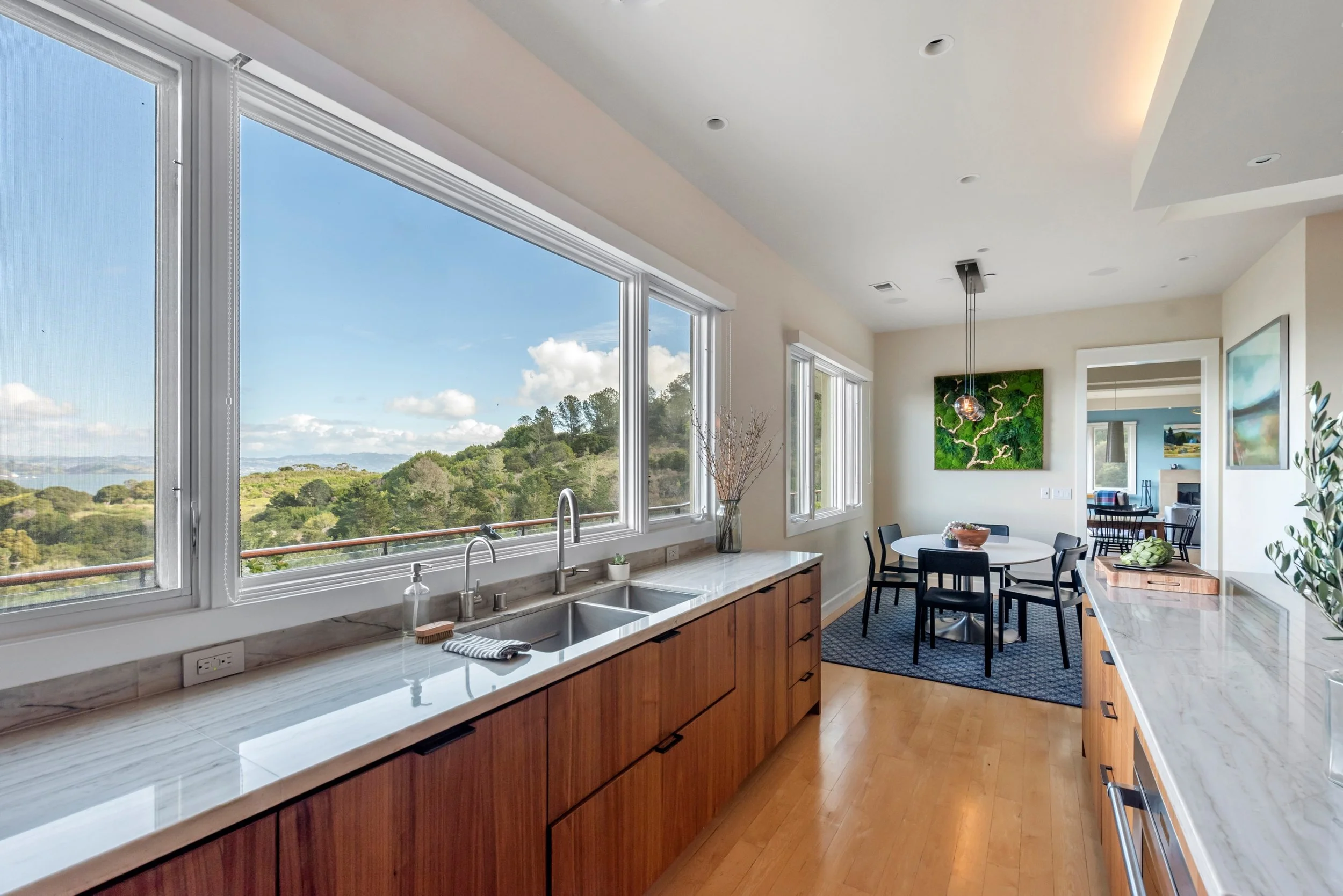 Luxury kitchen renovation in Belvedere-Tiburon designed by Marin interior designer Studio SQUIRE featuring walnut cabinets, matte black, cabinet hardware, quartzite countertops, Subzero Wolf appliances, and panoramic views of the San Francisco Bay.