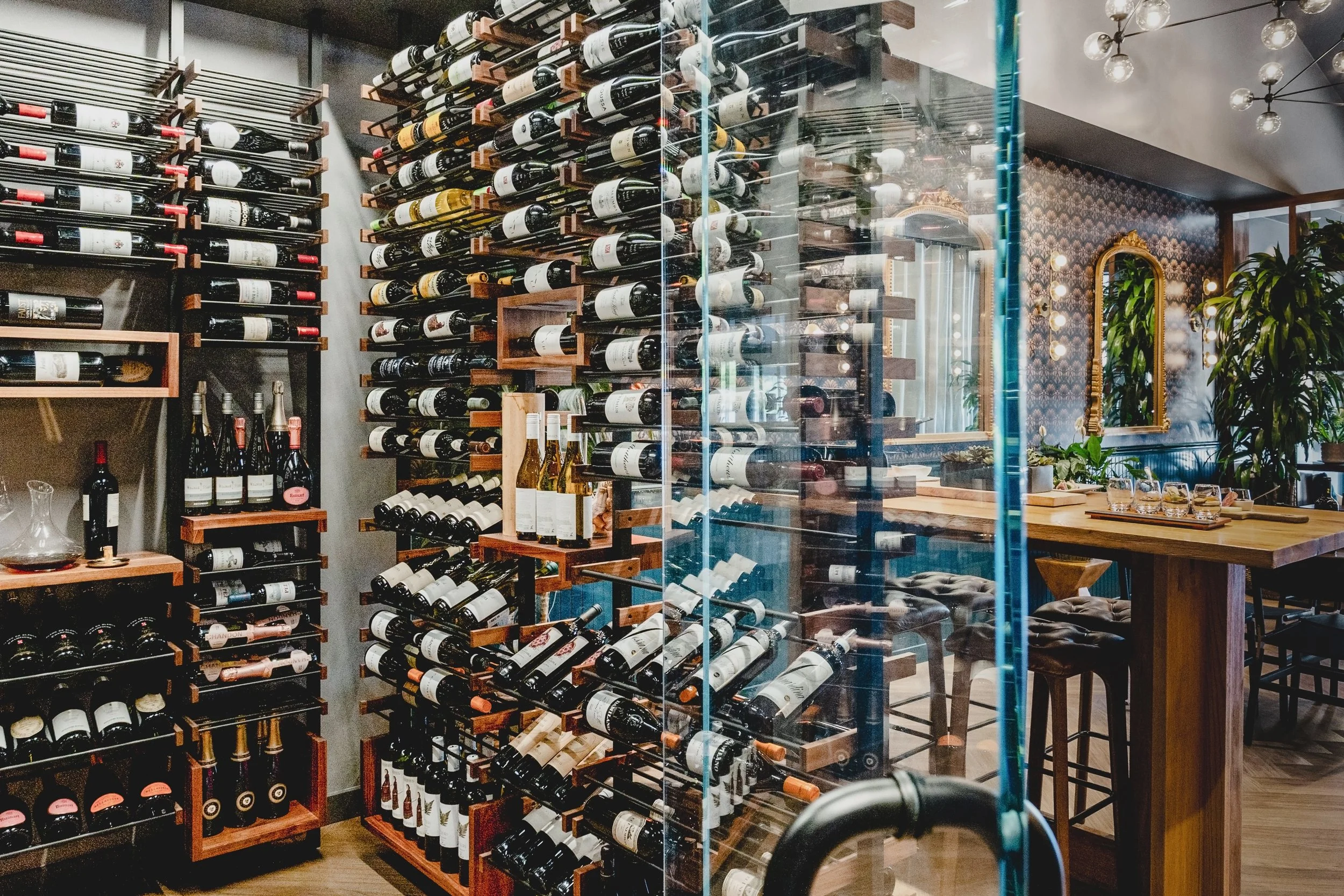 Commercial wine bar renovation in Belvedere-Tiburon designed by Marin interior designer Studio SQUIRE featuring Glass Door, Custom Wood Wine Rack, Patterned Wallpaper, and Brass Mirrors