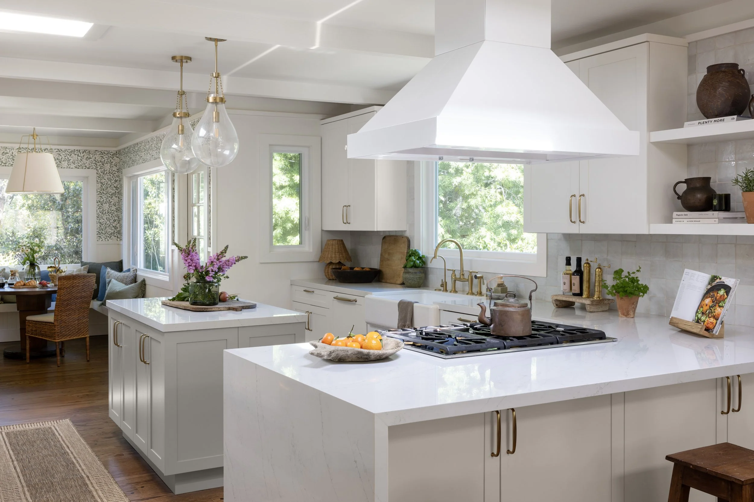 Kitchen renovation in Kentfield designed by Marin interior designer Studio SQUIRE featuring hana sky quartz, tile backsplash, brass hardware, wood stools, and pendant lighting