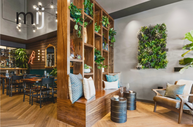 Wine bar renovation in Tiburon designed by Marin interior designer Studio SQUIRE featuring wood shelving, accent pillows, plant wall, and lounge seating