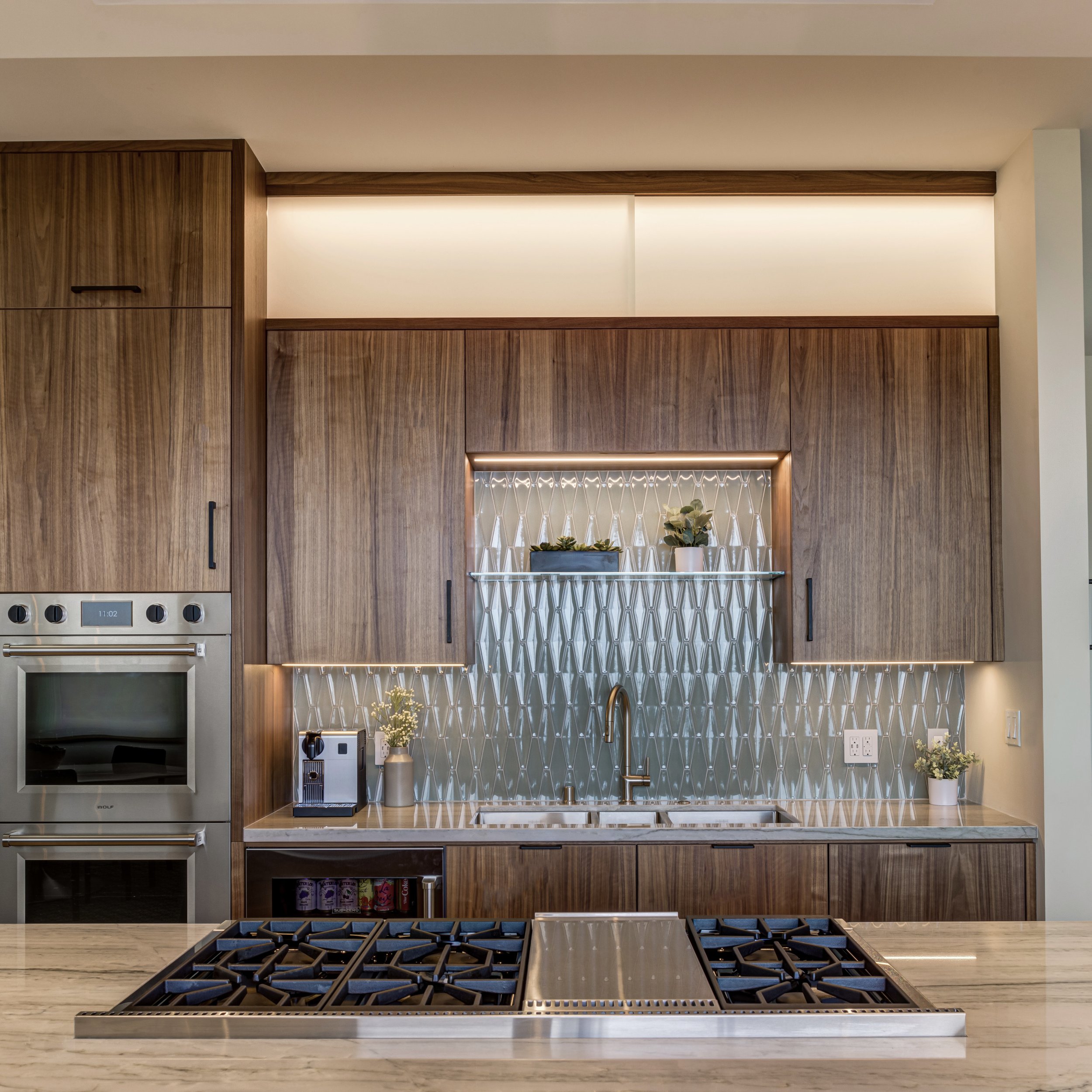 Luxury kitchen renovation in Belvedere-Tiburon designed by Marin interior designer Studio SQUIRE featuring walnut cabinets, matte black, cabinet hardware, quartzite countertops, Subzero Wolf appliances, and panoramic views of the San Francisco Bay.