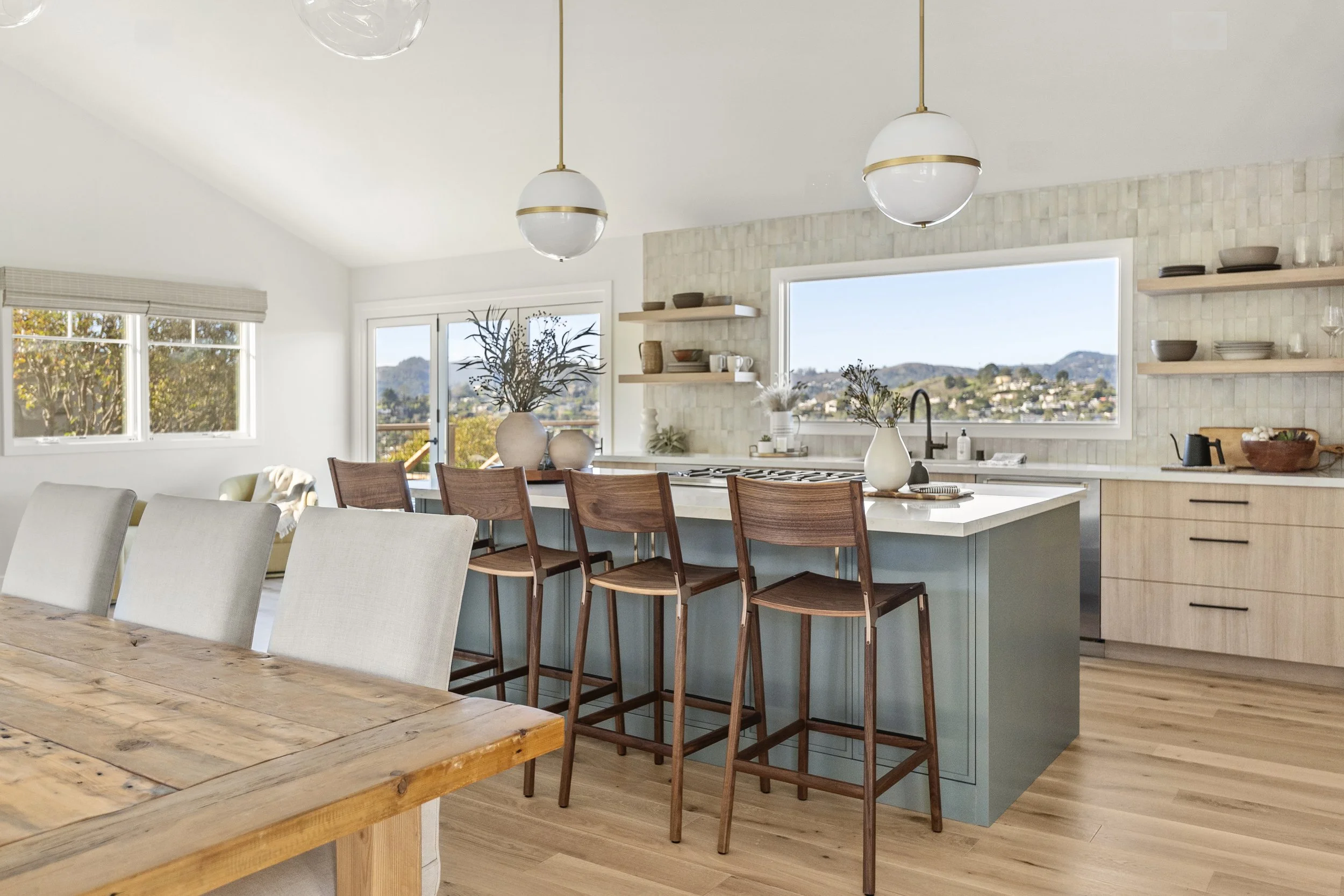 Kitchen renovation in Belvedere-Tiburon designed by Marin interior designer Studio SQUIRE featuring custom white oak cabinets, a sage green island, transitional pendant lights, large windows, and a folding glass door to the deck.