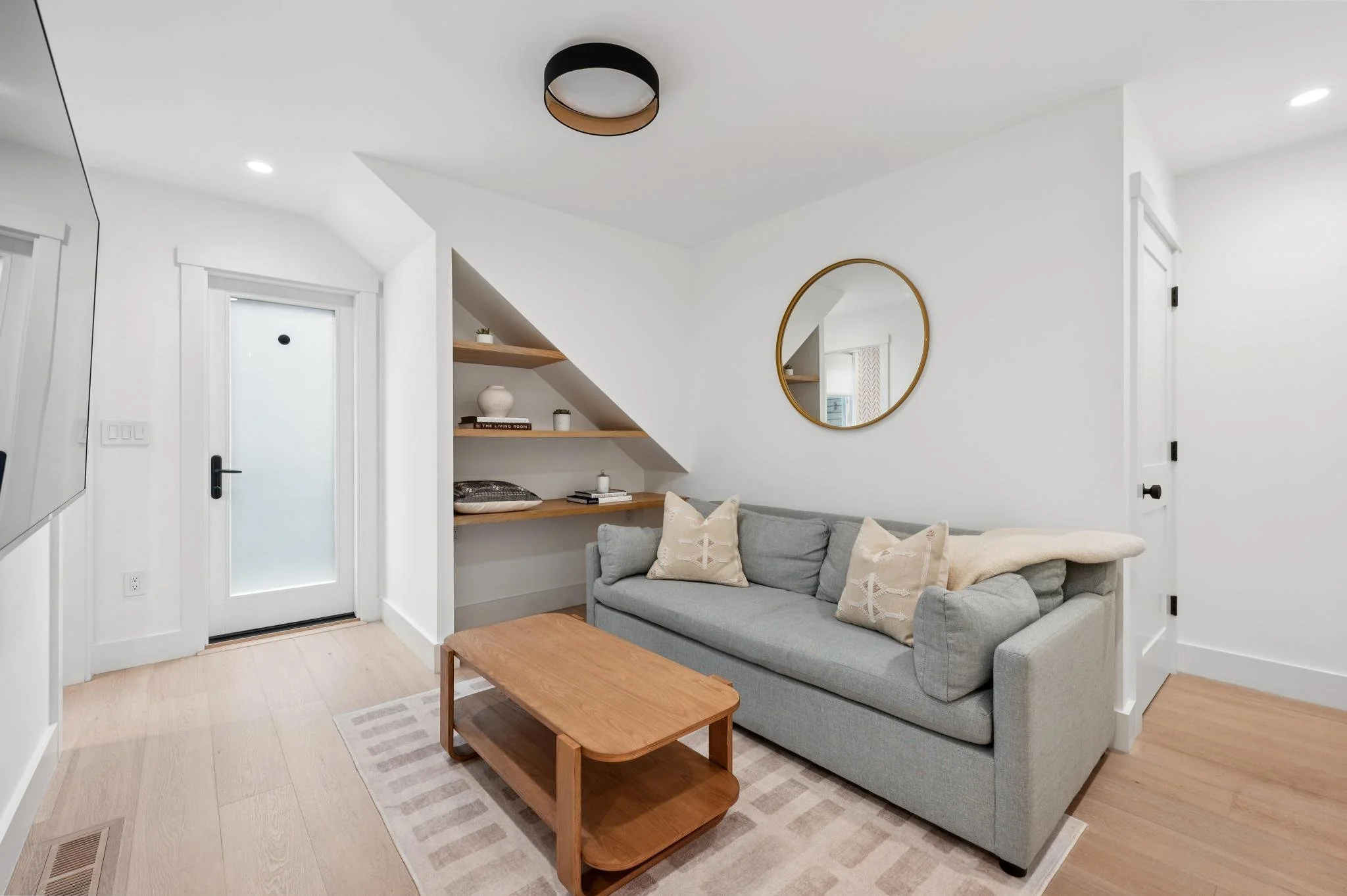 Den renovation in San Anselmo designed by Marin interior designer Studio SQUIRE featuring Accent Rug, Wood Coffee Table, Shelves, and Grey Couch..
