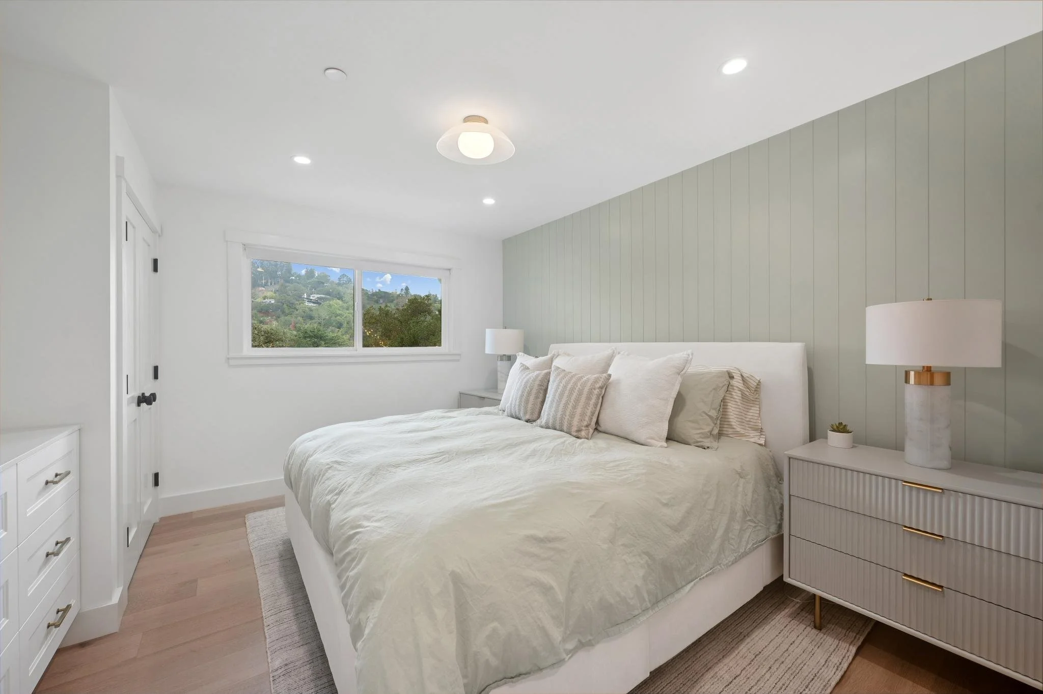 Primary Suite renovation in San Anselmo designed by Marin interior designer Studio SQUIRE featuring Shiplap Wall, Pendant Light, Nightstands, and White Bed.