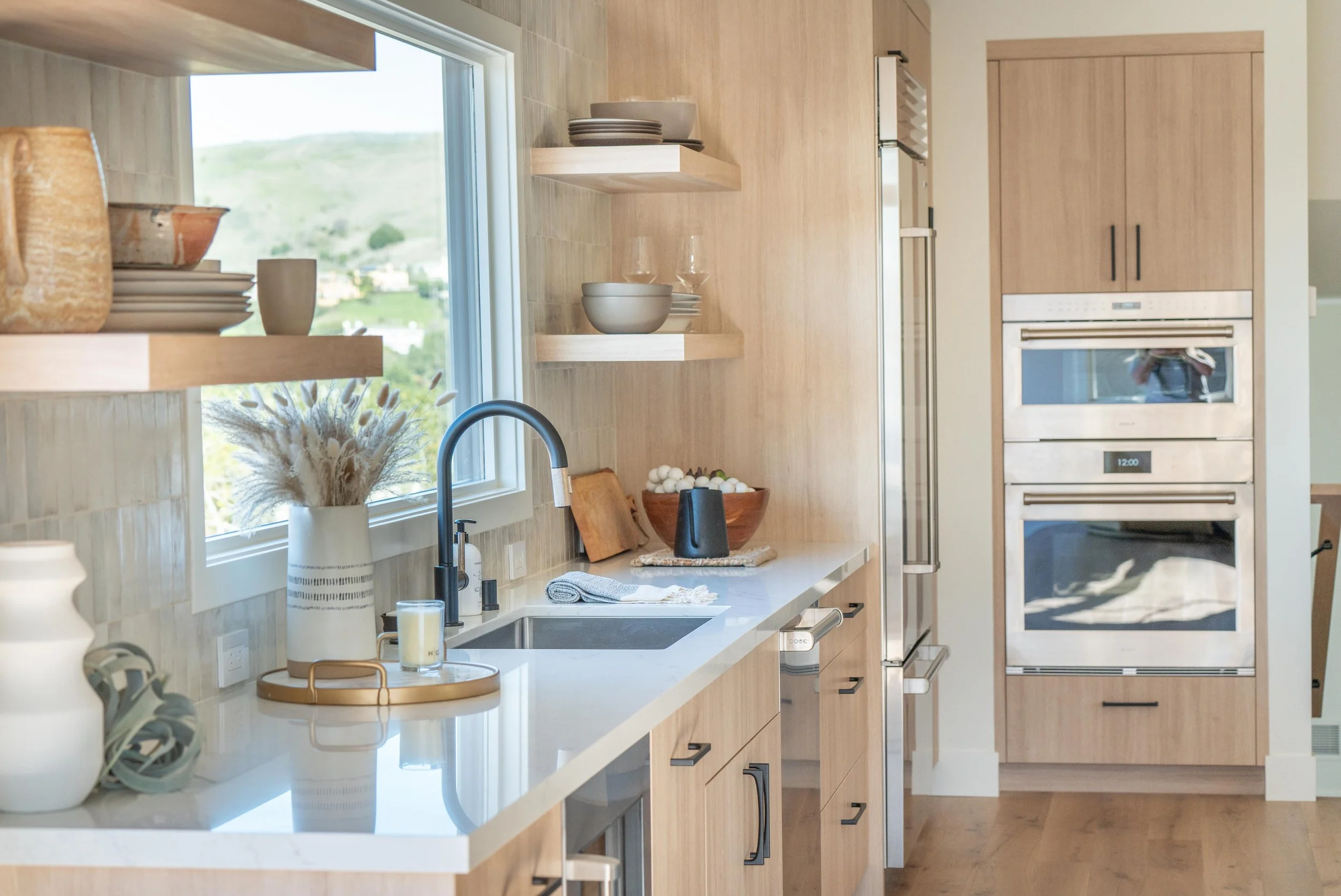 Kitchen renovation in Tiburon designed by Marin interior designer Studio SQUIRE featuring white oak custom cabinets, open shelving, matte black hardware, and Subzero Wolf appliances.