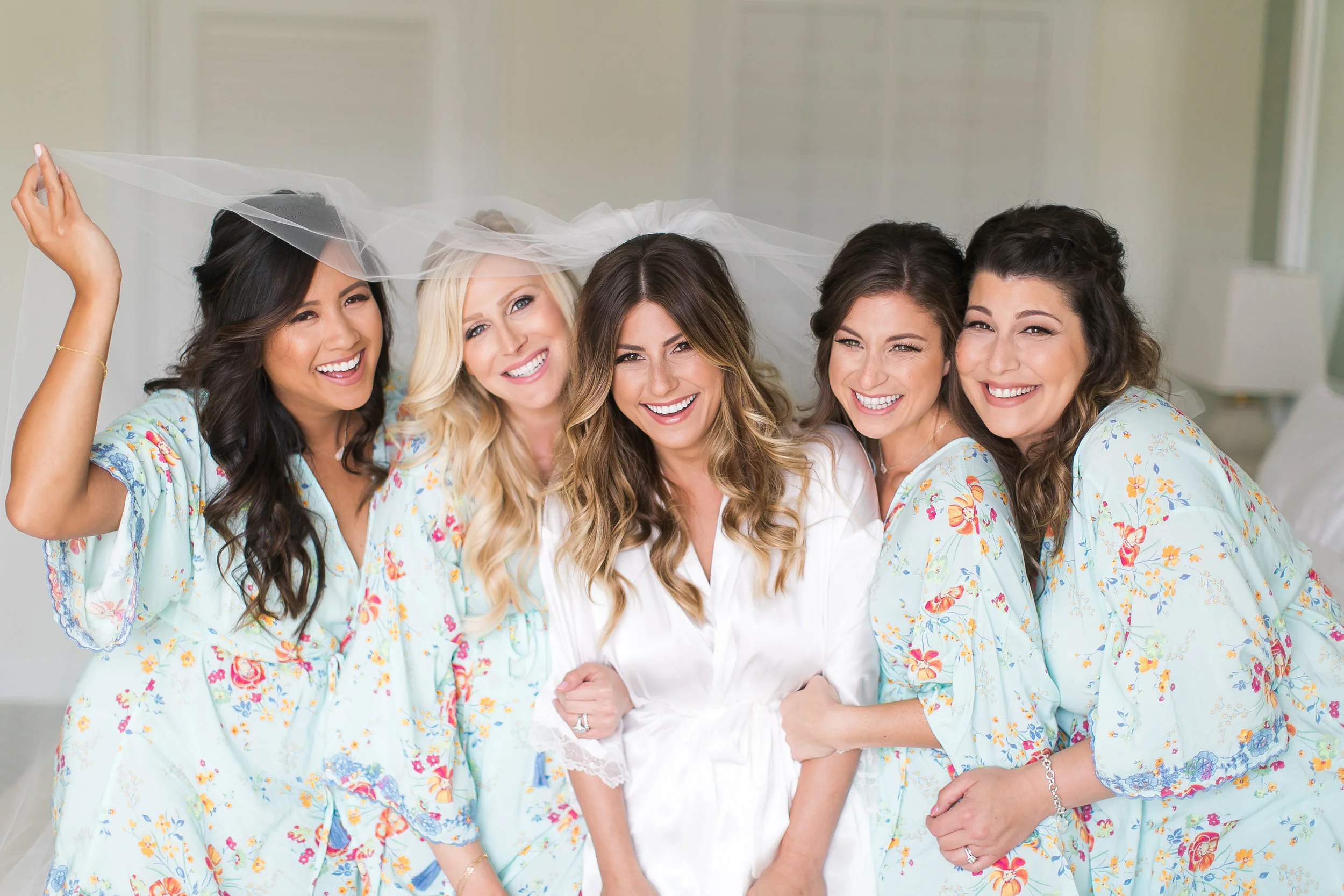 Bridesmaids in robes under bride's veil