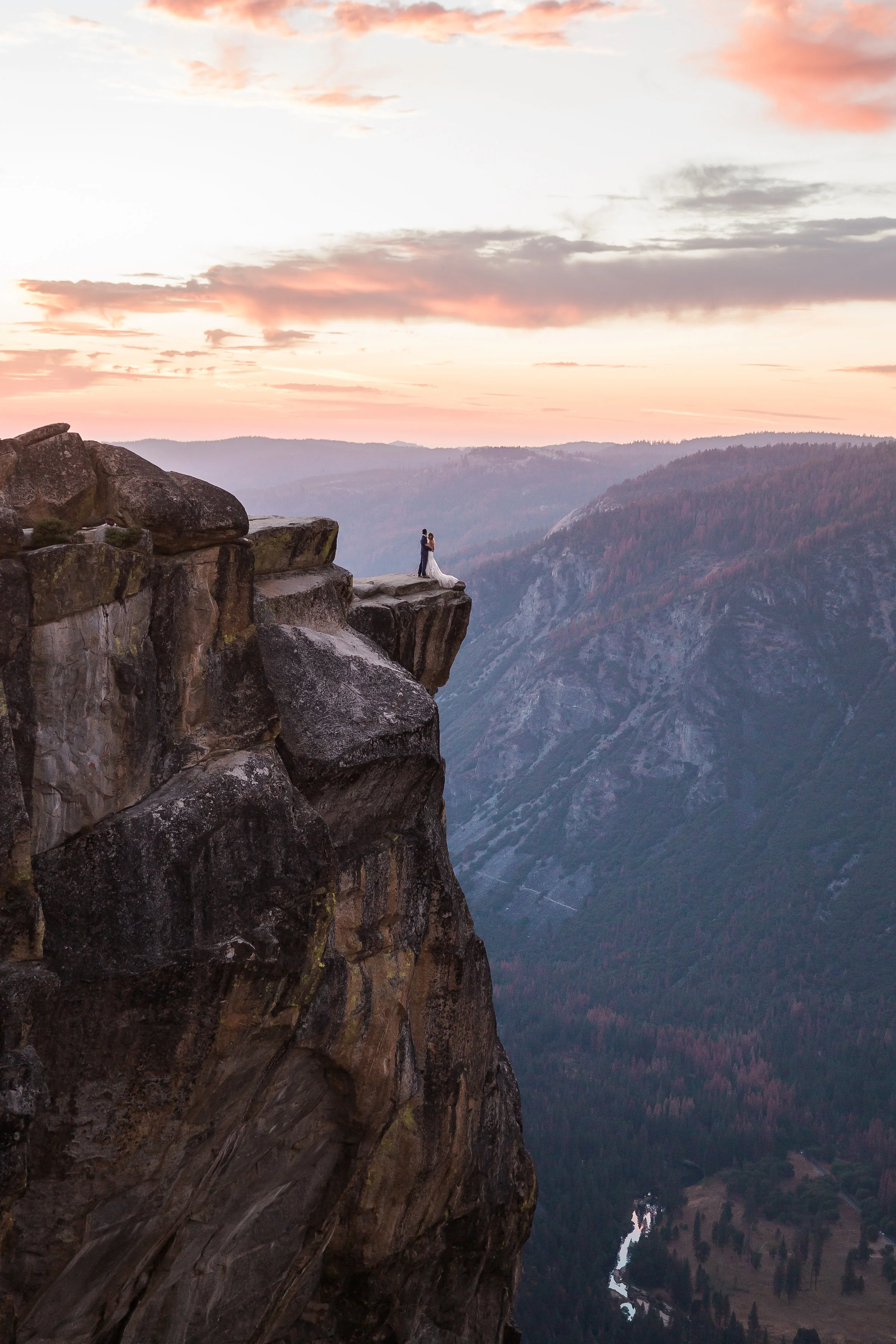 bride and groom stand on taft point at sunset