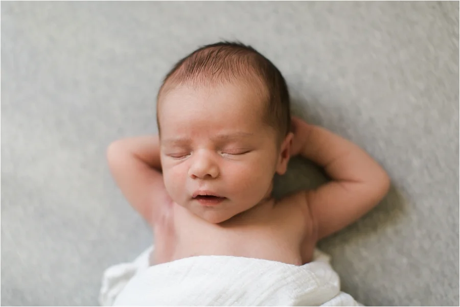 Elliott was asleep in his crib next to a large window when I attempted this shot. The simple grey sheet against the white swaddle cloth keep the photo clean and the focus on the baby. While I was posing his arms this way I hovered above him loudly whispering, "SHHHHHHHH." 