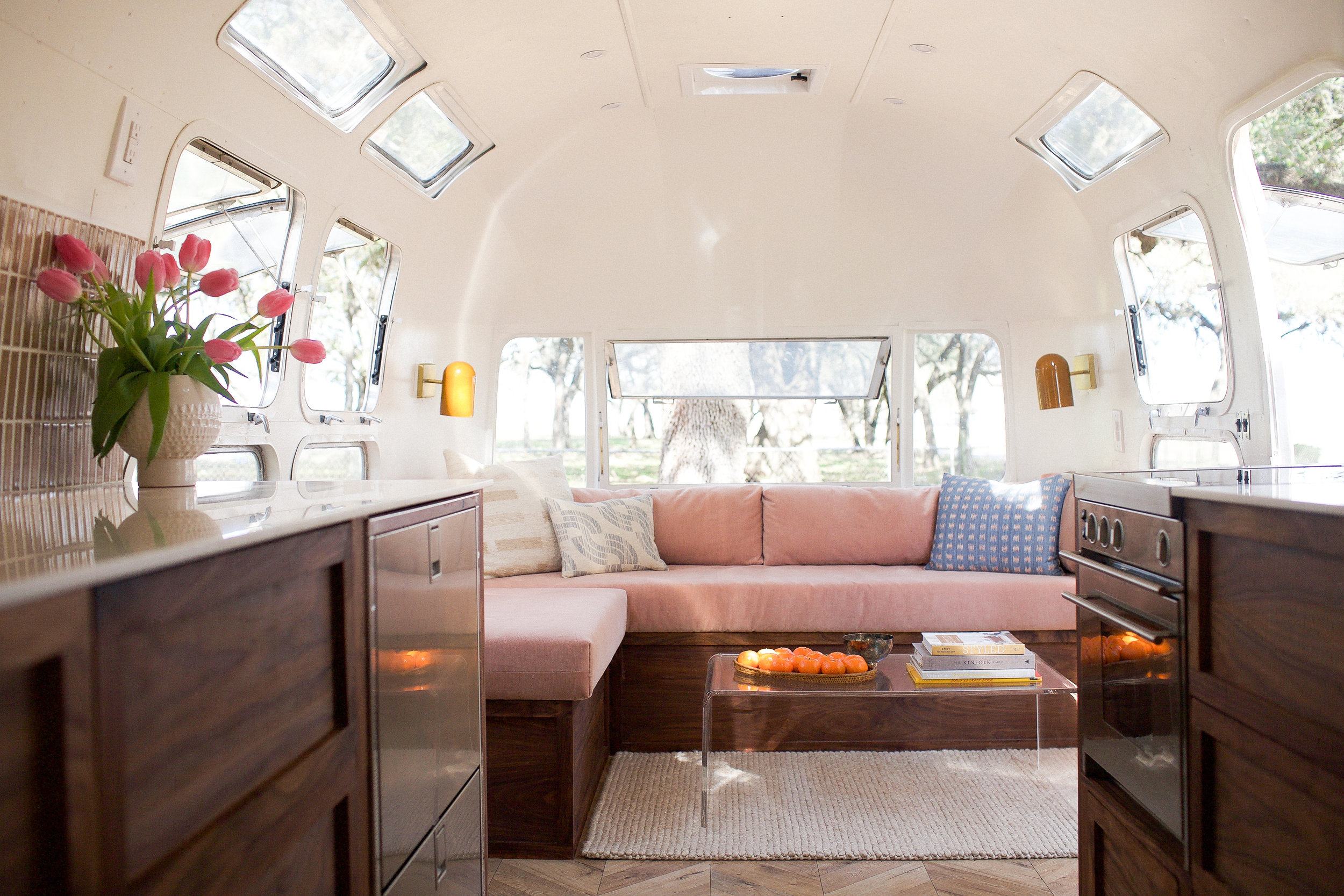 A beautiful airstream with soft pink furnishings and dark wood kitchen
