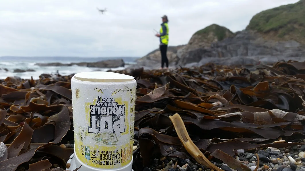 Drone Pilot and Mission Director passing a lonely pot noodle on Hemmick Beach, Cornwall.
