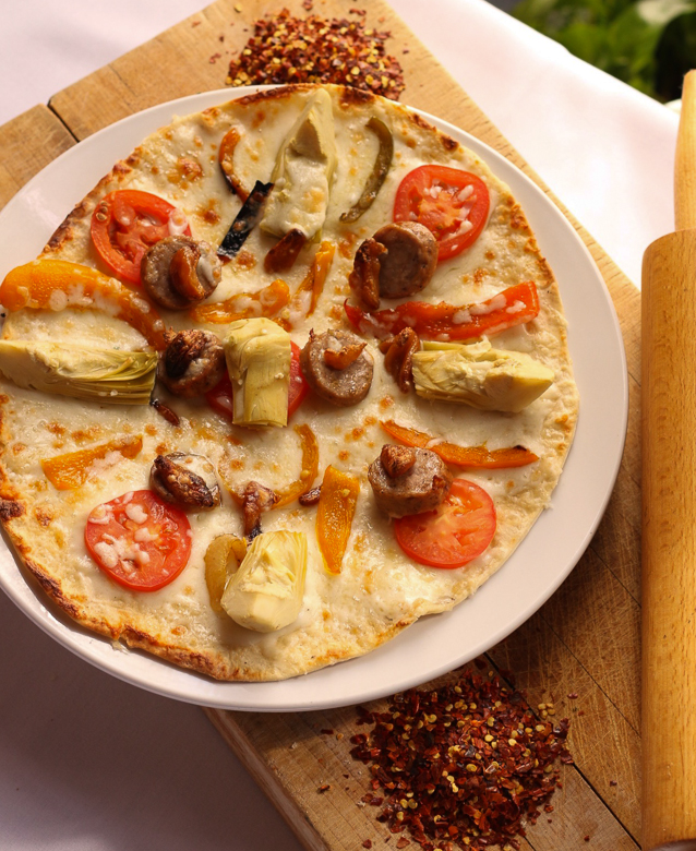 Aurora Pizza Italian sausage, mozzarella, fontina, artichokes, roasted garlic, peppers, onions, tomatoes, Marsala parmesan cream sauce
