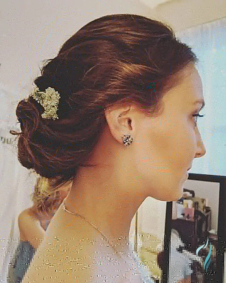 Elegant low chignon updo and floral hair accessory by Changing Times Hair Designs, State College, PA.