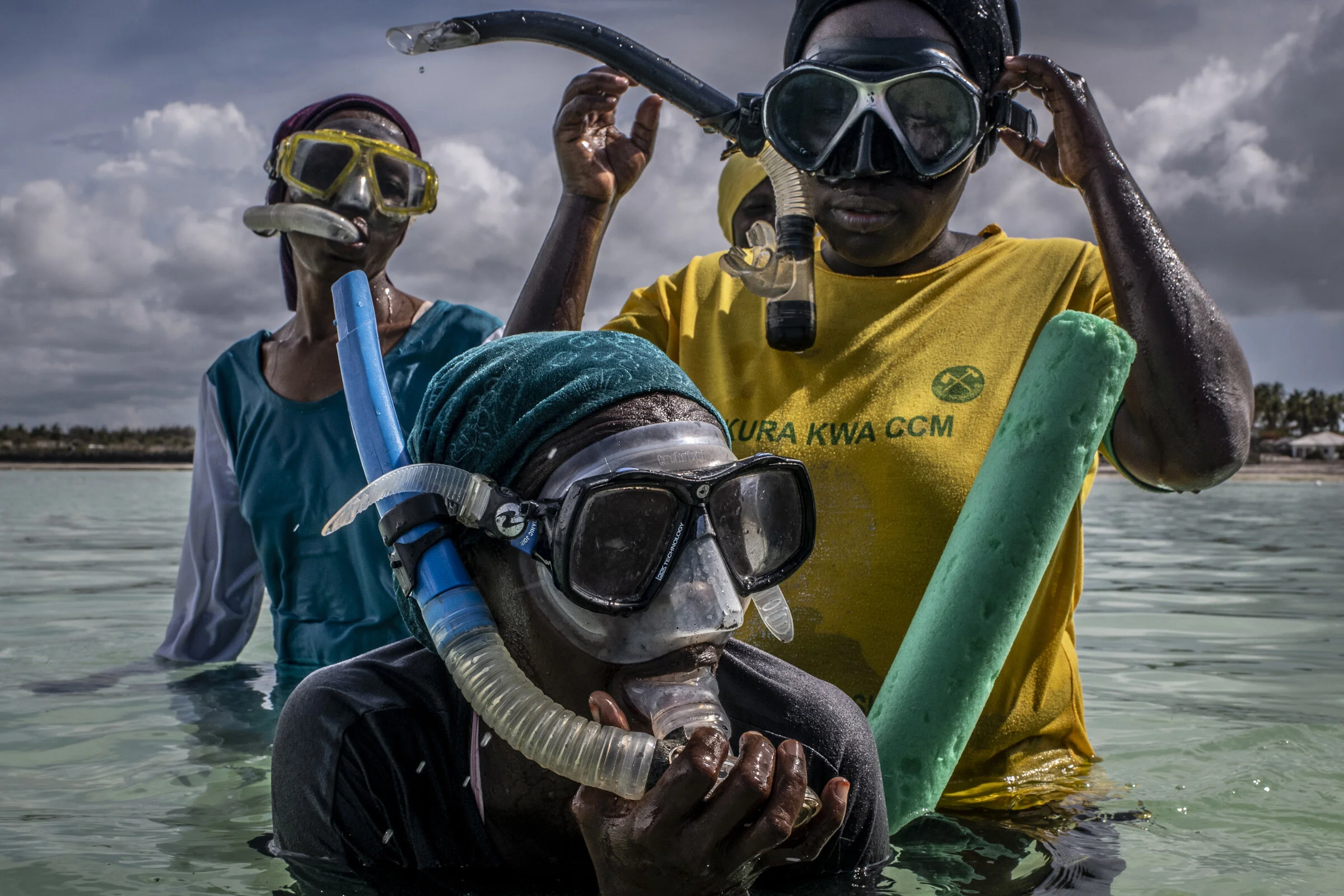 Single mother sponge farmers practice breathing wearing mask and snorkels during their swim lesson.