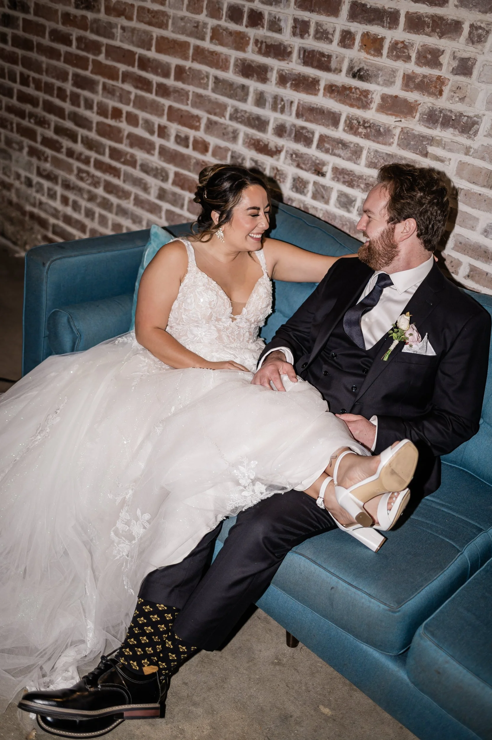 A newlywed couple sitting on a couch together laughing