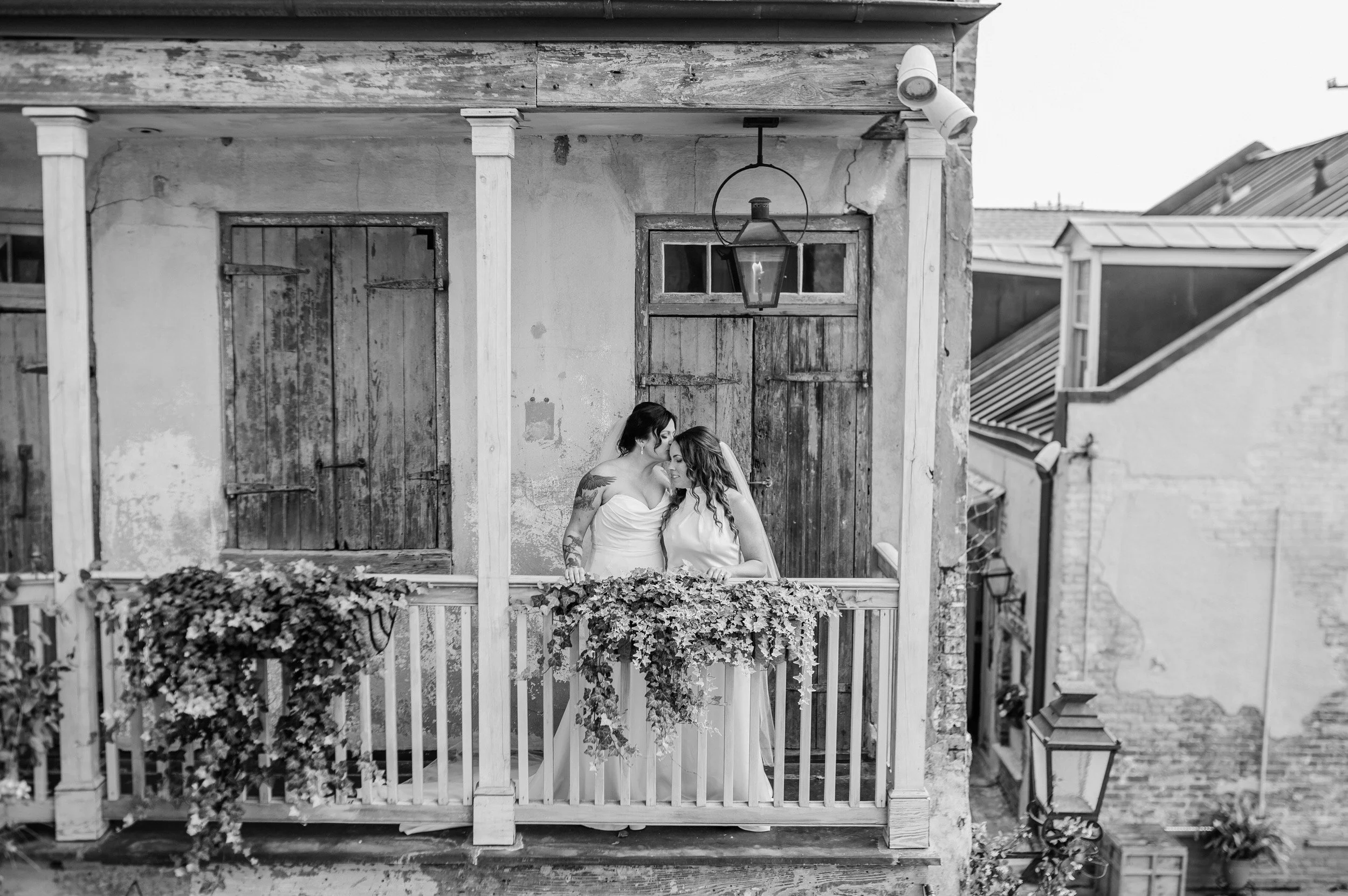 A newlywed kissing their partner's forehead as they stand on a small porch
