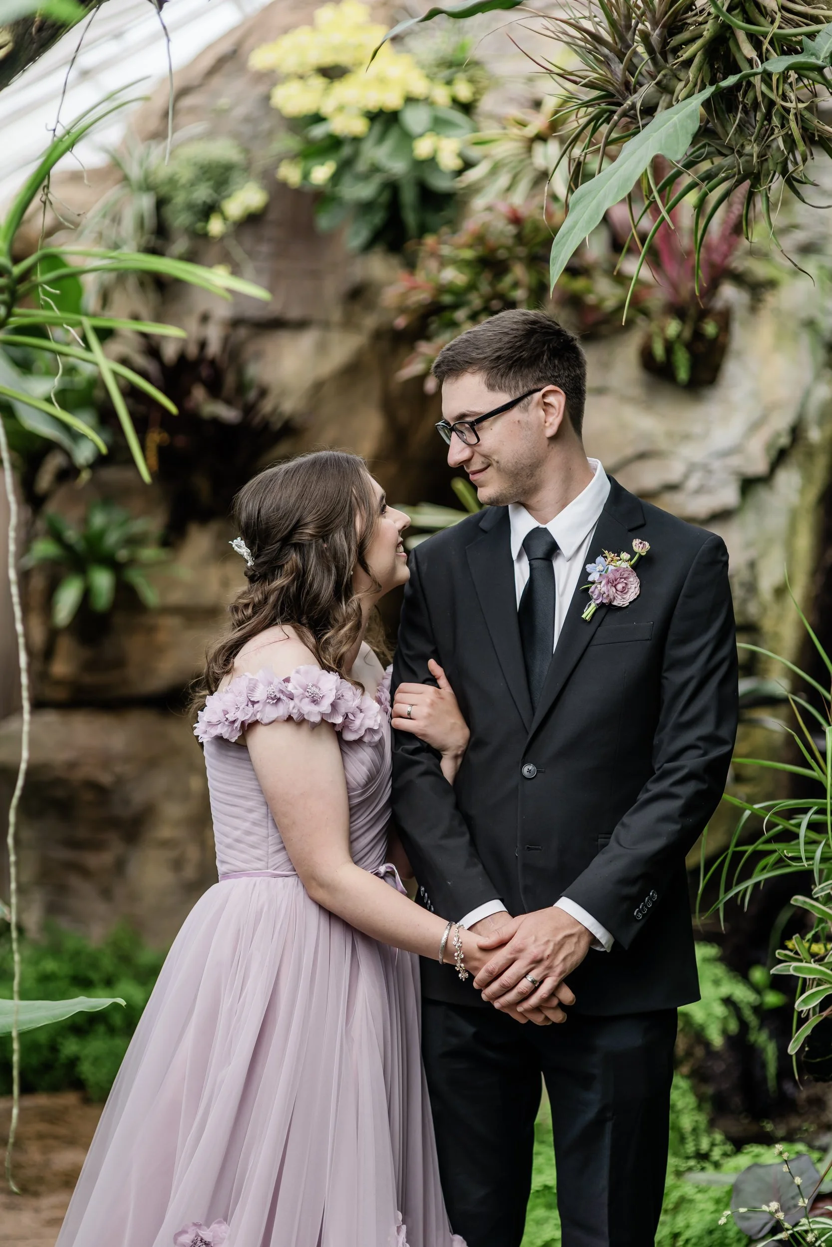 A newlywed with their arm wrapped around their partner's as they smile at each other