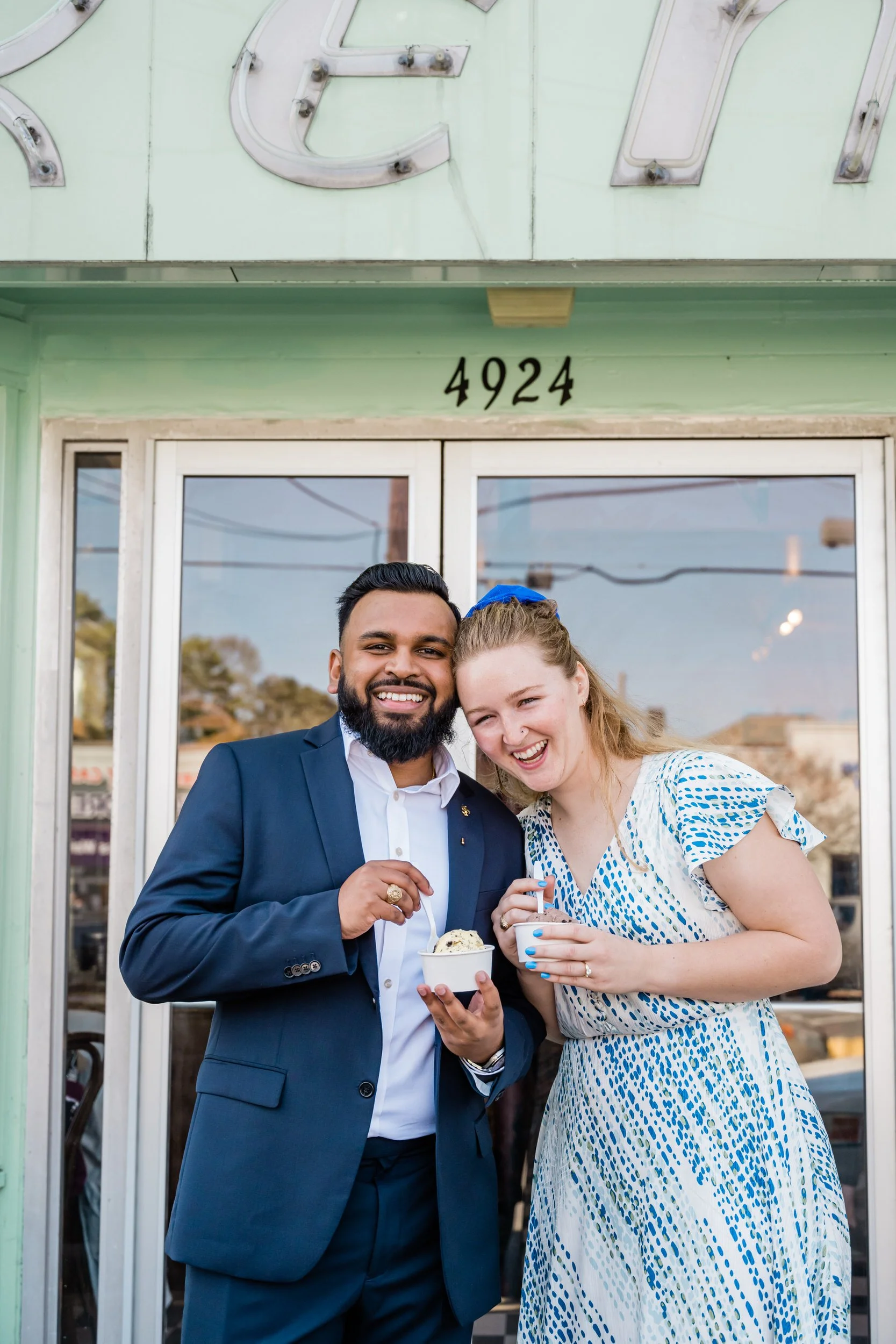 A couple smiling and leaning into each other while holding ice cream