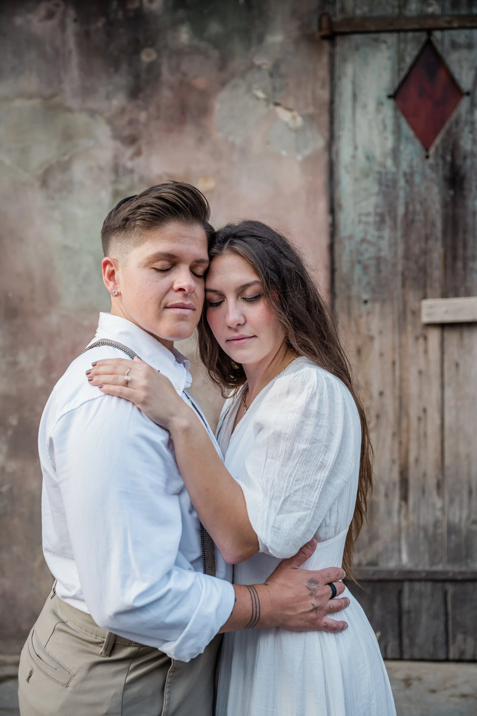 A couple with their arms around each other as one leans into the other 