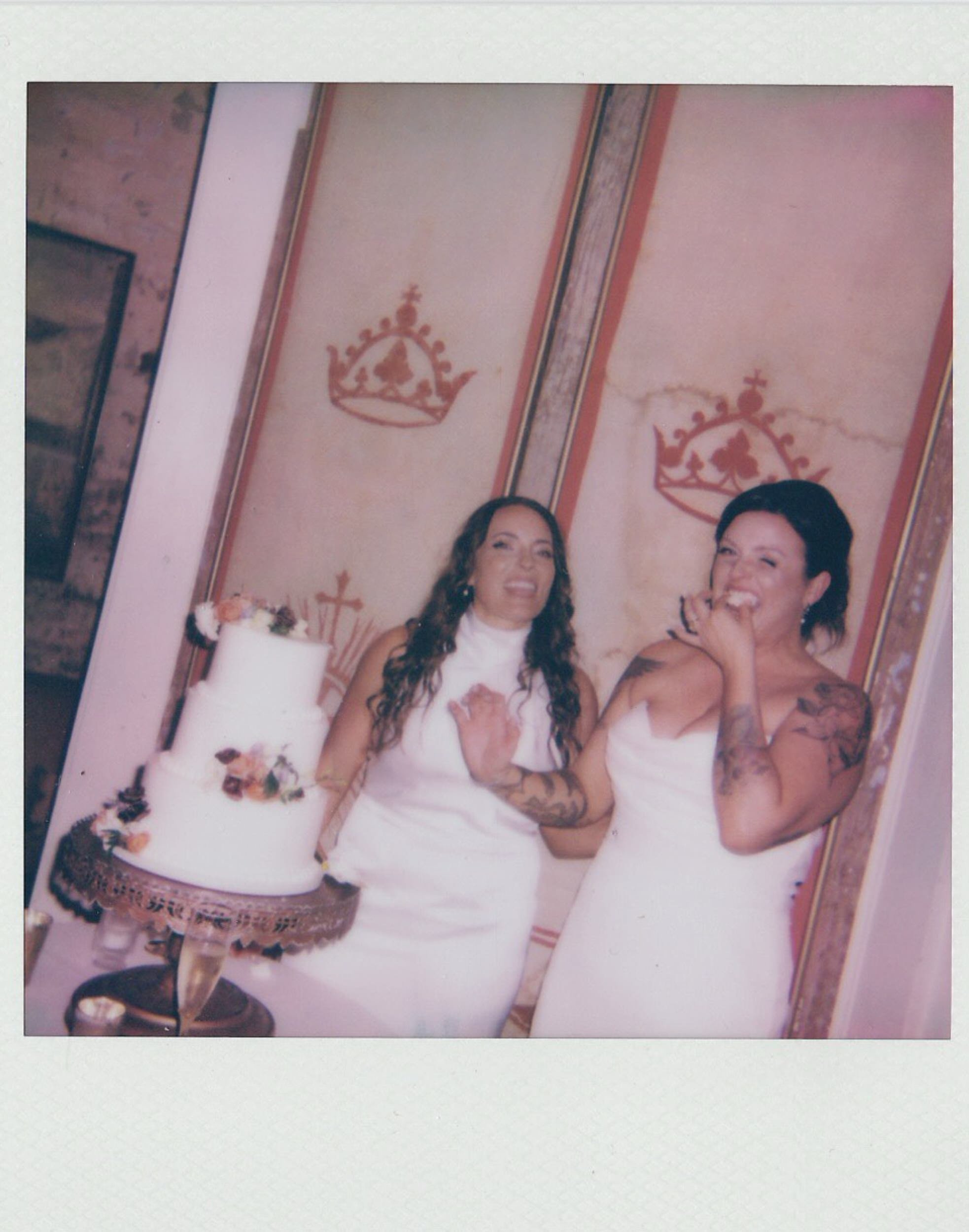 A polaroid of a newlywed couple laughing as they cut their wedding cake